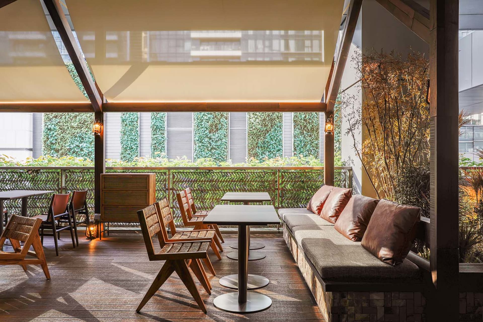 A modern outdoor living space with a wooden floor, a patio table, a couch, a dining table, and several chairs, creating a comfortable and inviting atmosphere