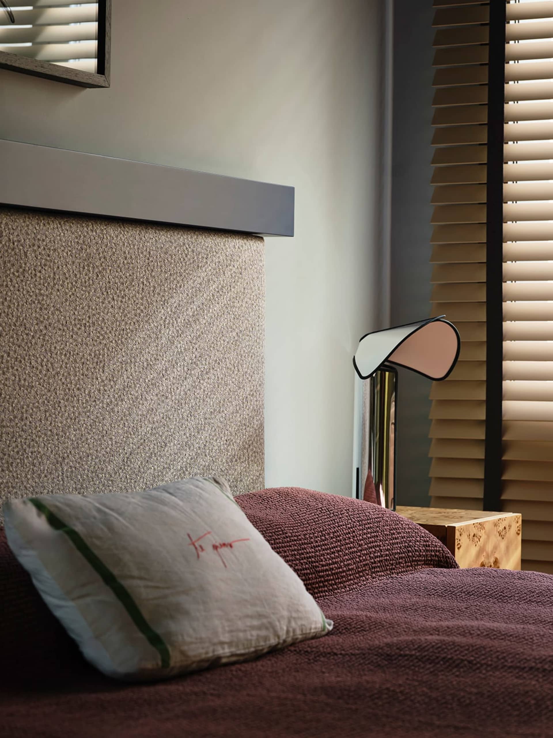 Cozy bedroom with a bed, a wooden table, and a lamp, set against a dimly lit background