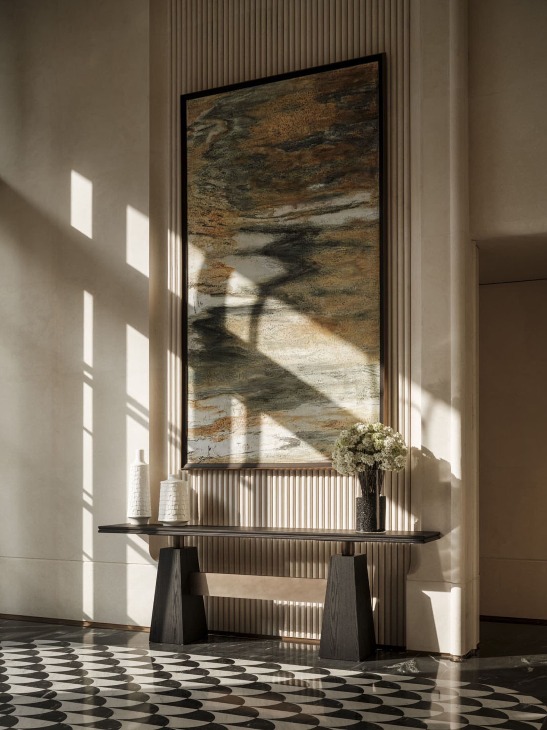 A well-lit room with a modern art piece on the wall, a vase, and a warm atmosphere