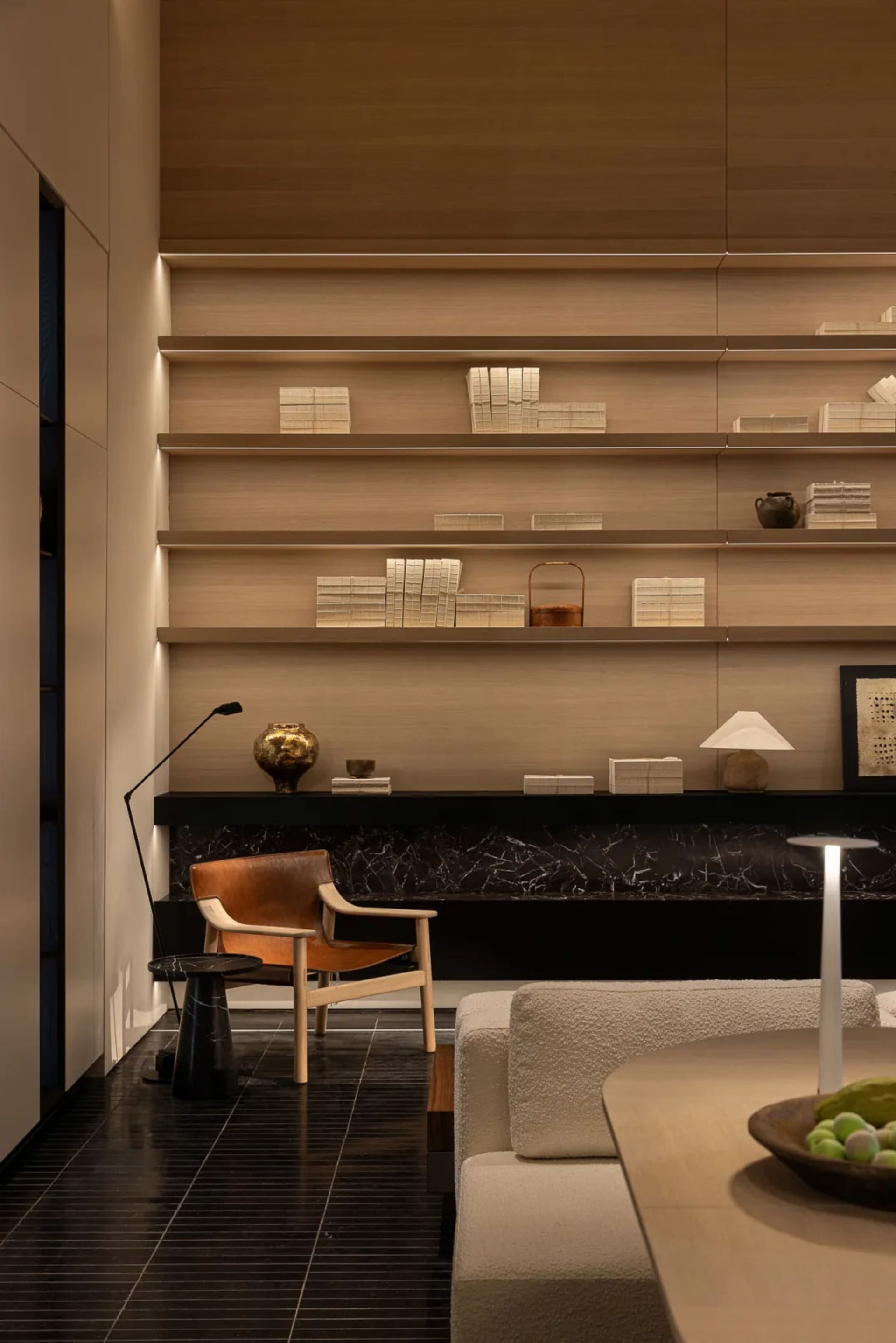 Cozy living room with a wooden floor, a couch, a chair, and a bookshelf with books, creating a warm and inviting atmosphere