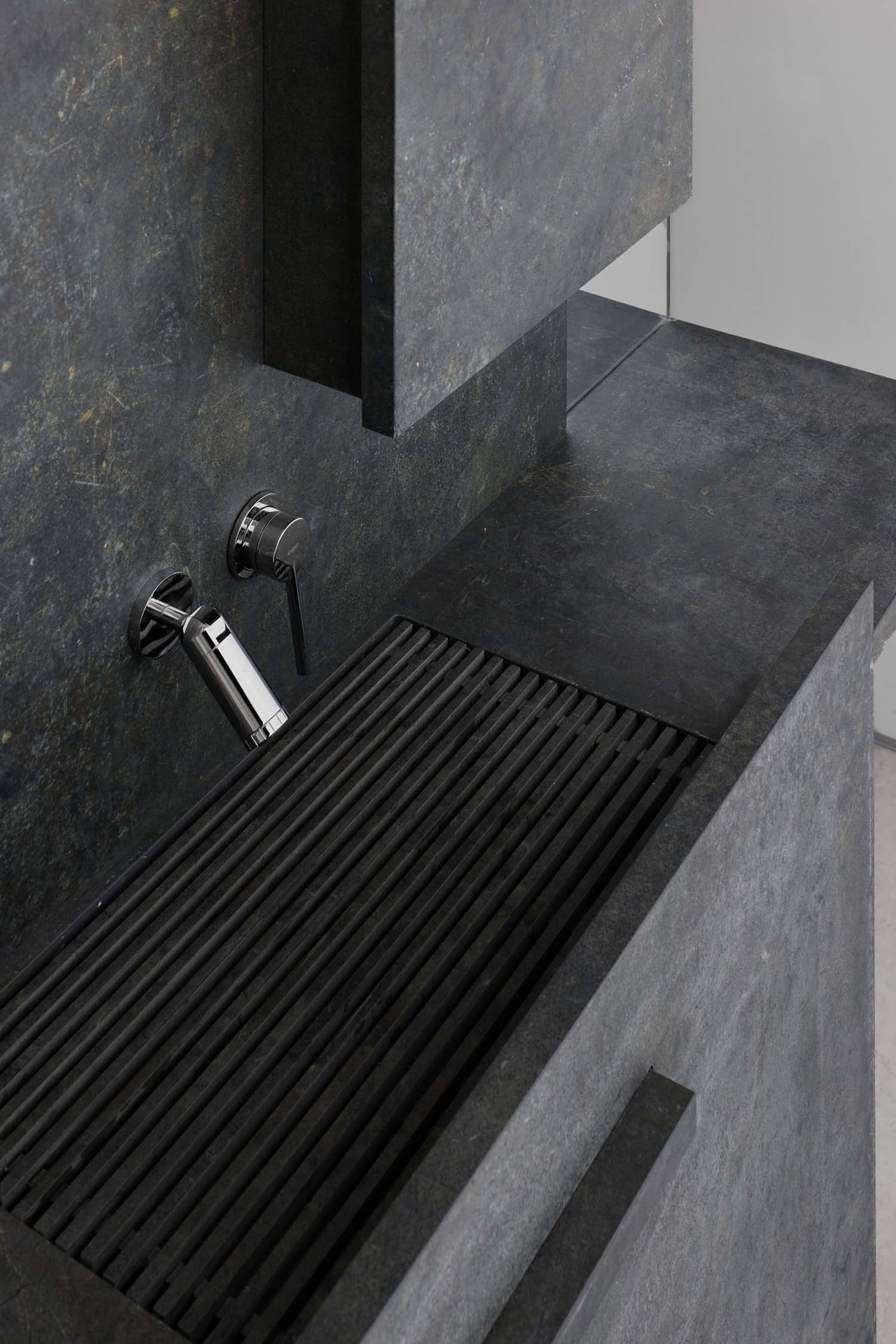 A modern kitchen counter with a stone surface and metallic sink, set in a dimly lit space