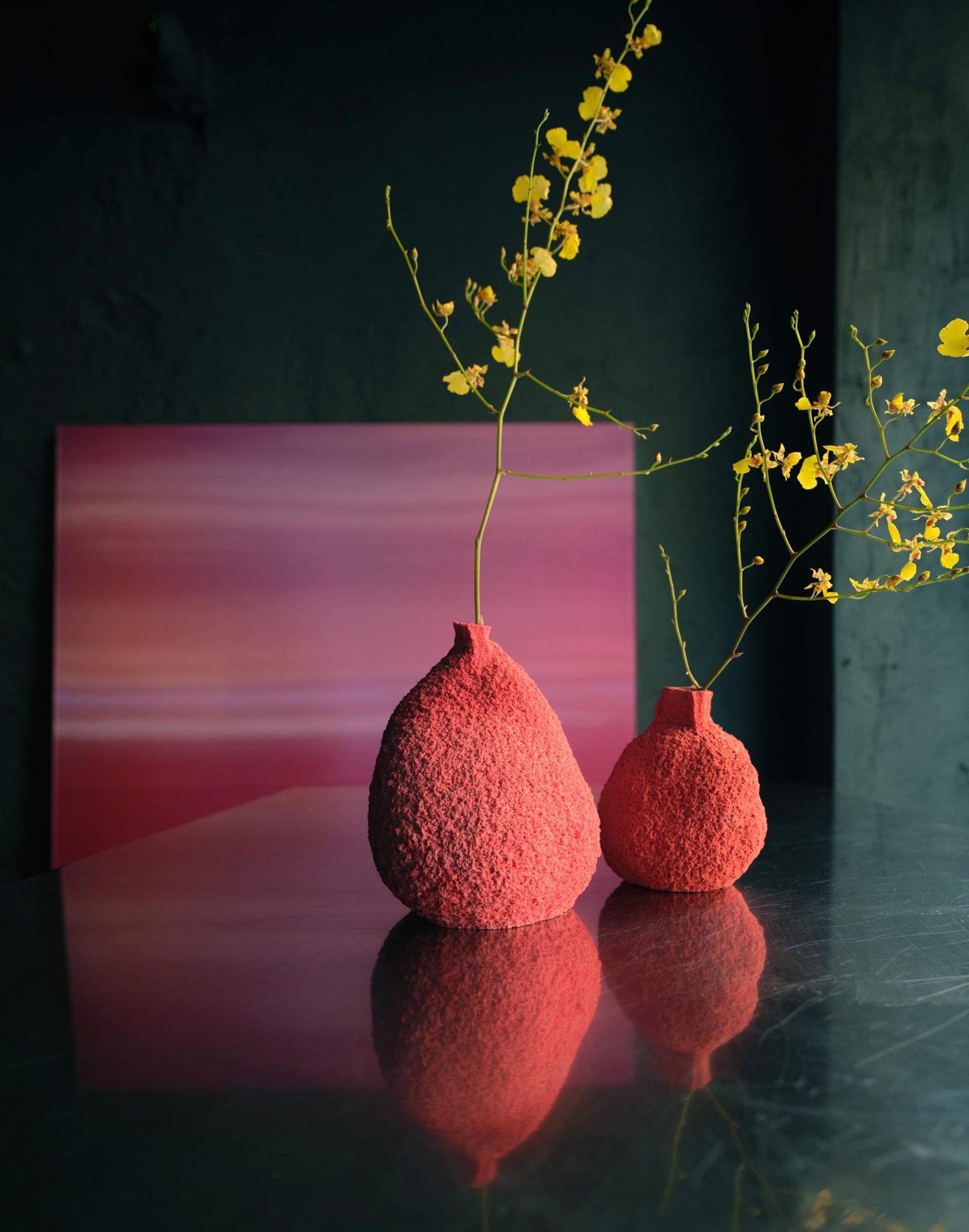 A dimly lit room with a pink wall and two red vases on a table, the main focus of the scene