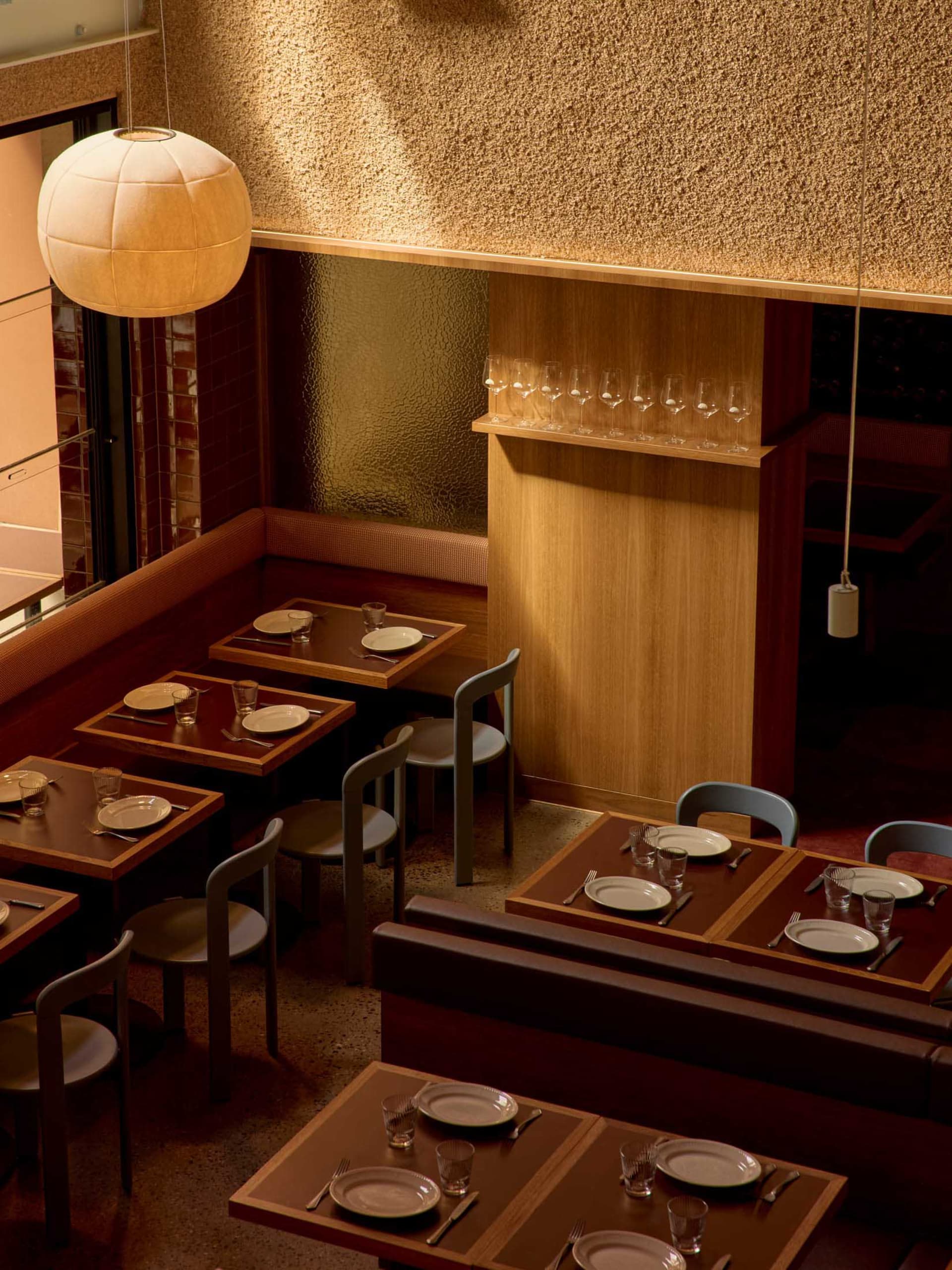 A well-lit restaurant interior with multiple tables, chairs, and wood elements, creating a warm and inviting atmosphere for guests