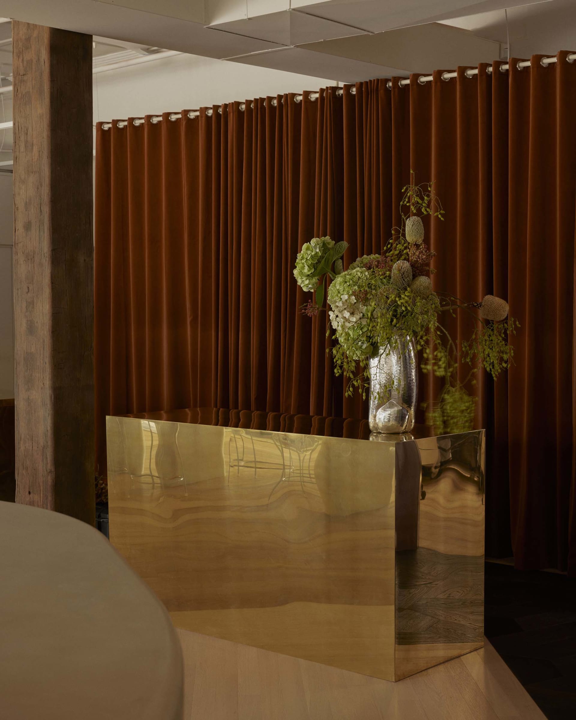 Dining area with a wooden countertop, brown curtain, and a vase with flowers on a table surrounded by chairs
