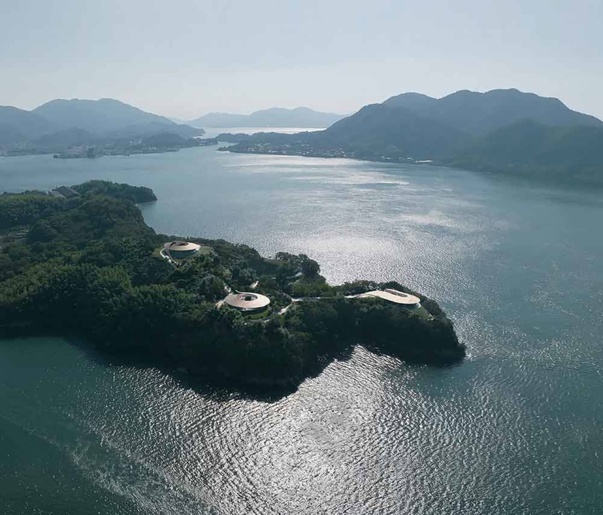 A serene modern house on a lake with a large deck and open spaces, surrounded by water and blending with its natural surroundings