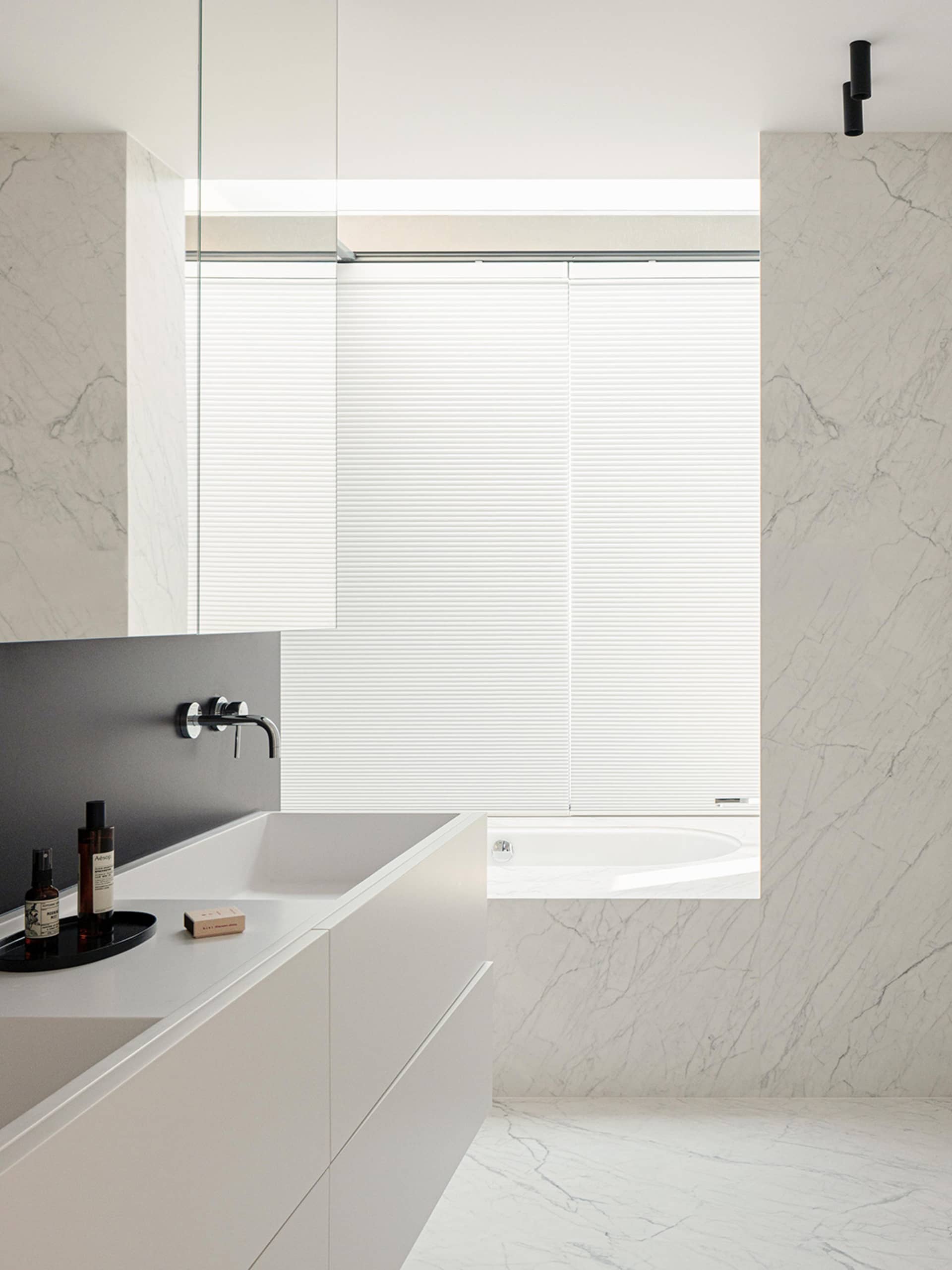 Bathroom with a sink, bathtub, and window, featuring a marble countertop and modern style