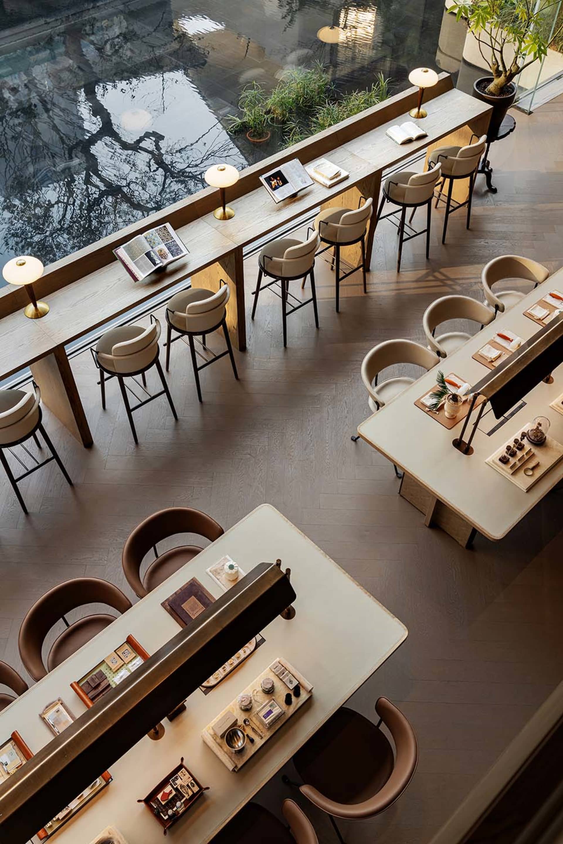 A modern restaurant with a large dining table and chairs, surrounded by additional seating and a mix of materials and colors, with soft and inviting lighting