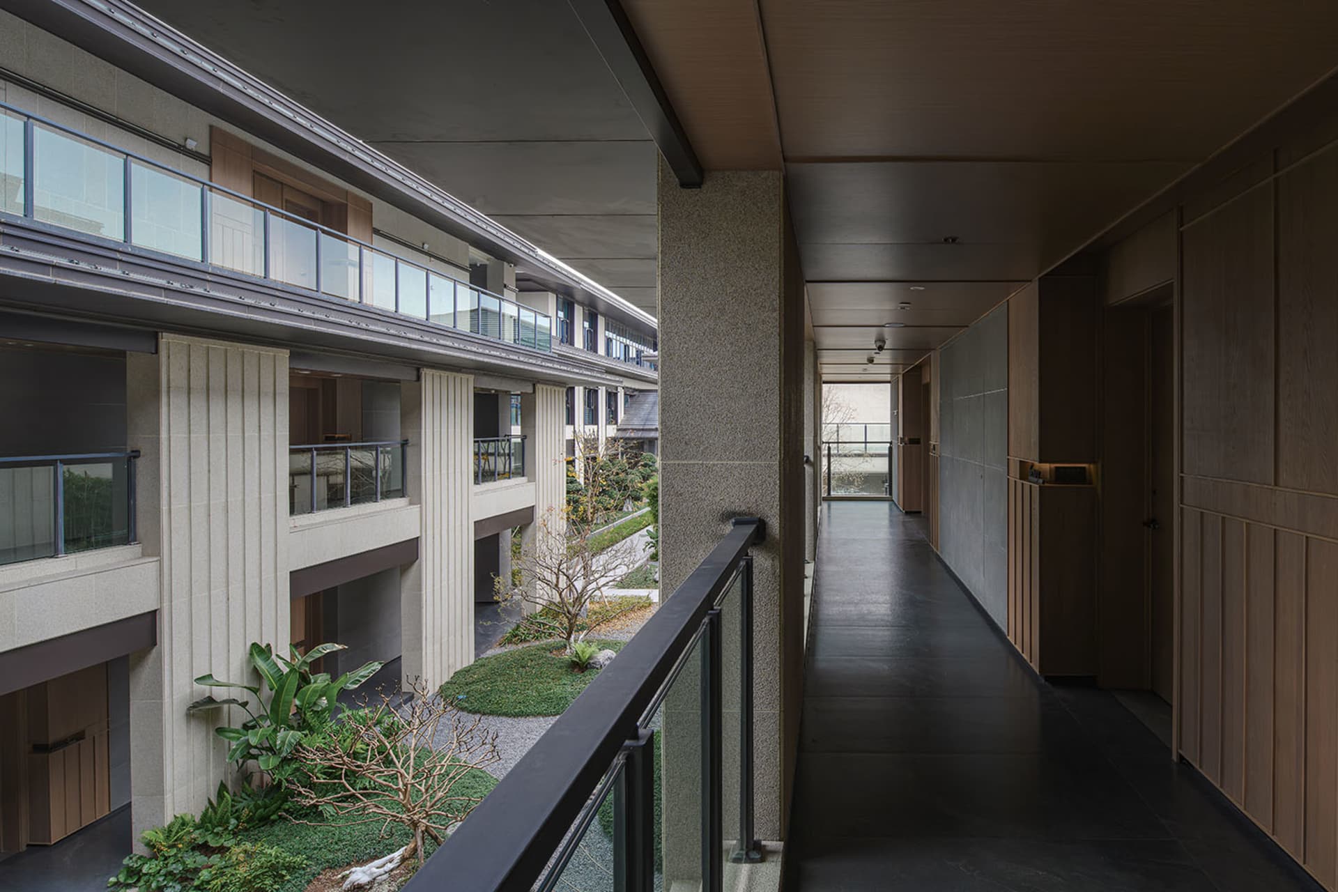 Photograph of a modern building with a glass balcony, offering a view of the surrounding area, well-lit and calm