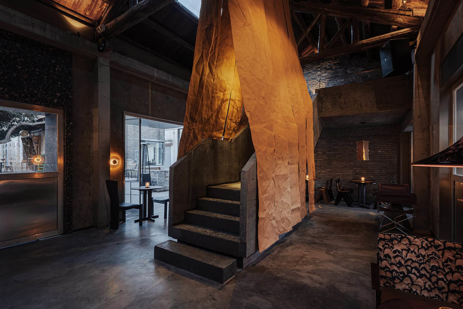 A restaurant with a stone wall, multiple chairs, and dining tables arranged throughout the room, creating an inviting and comfortable atmosphere