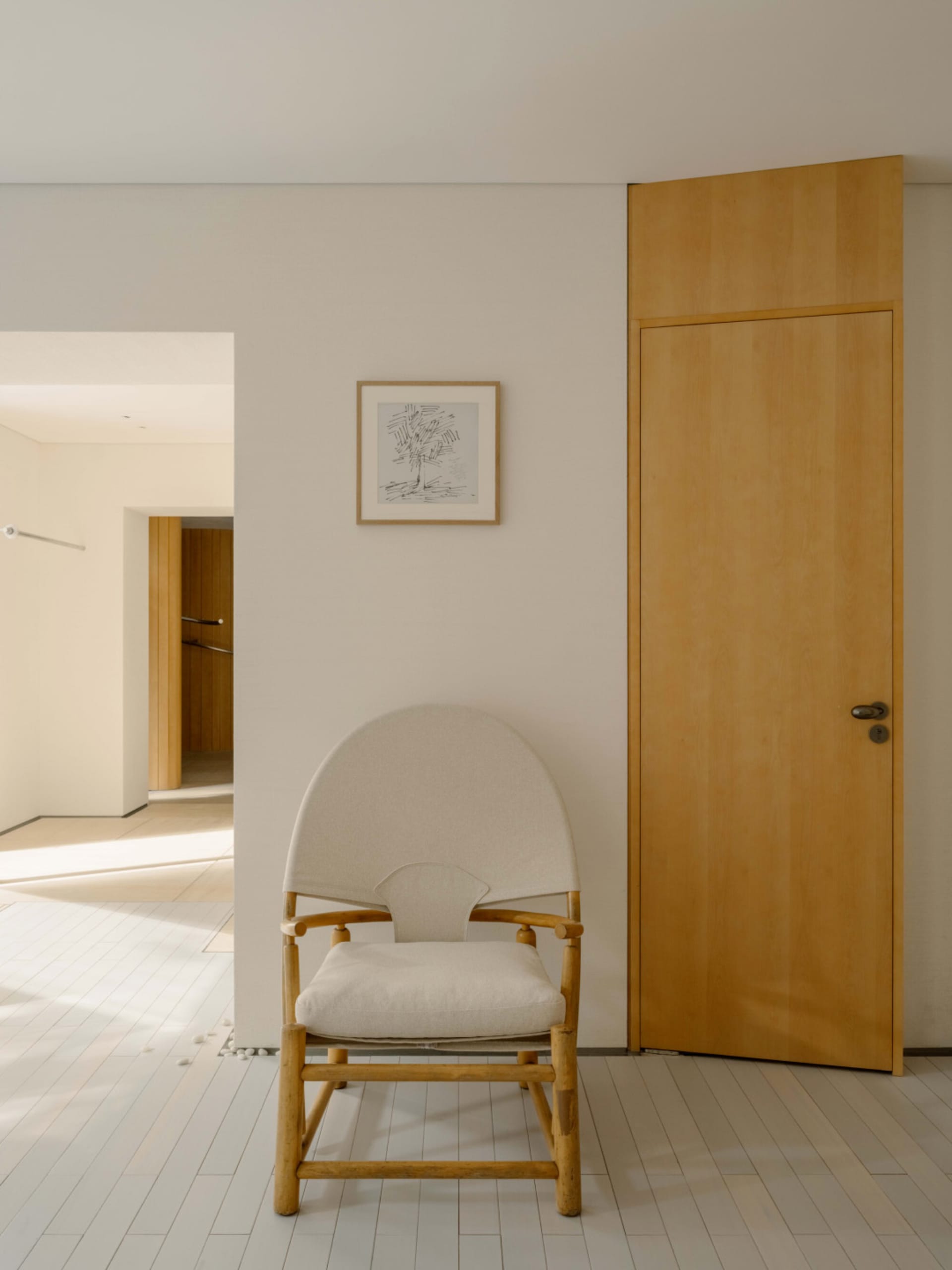 A modern living room with a white chair and wooden door, well-lit and inviting, with a focus on comfort and functionality