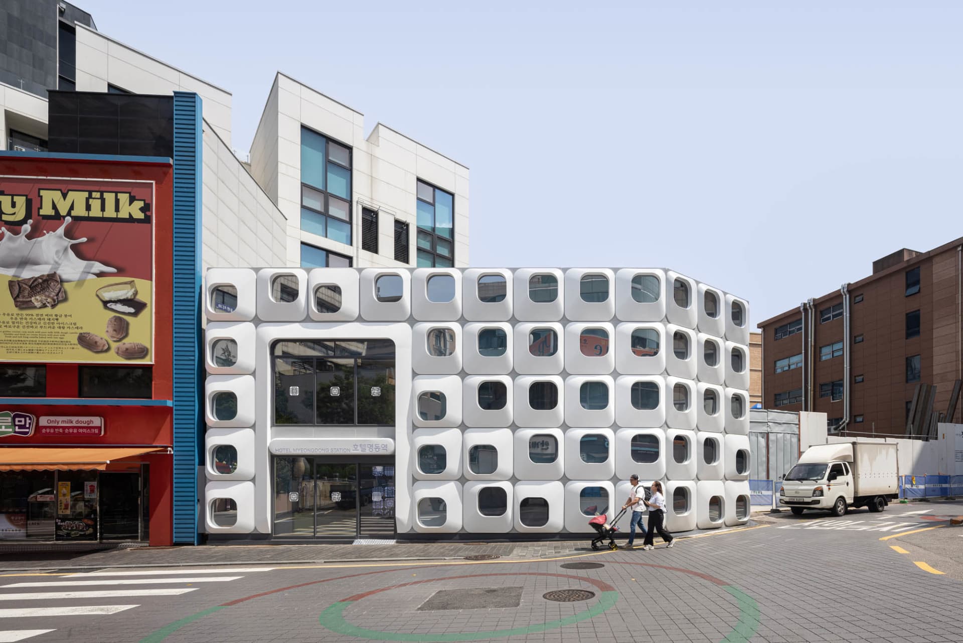 Photograph of a modern building with a circular shape and white facade in a busy urban city setting