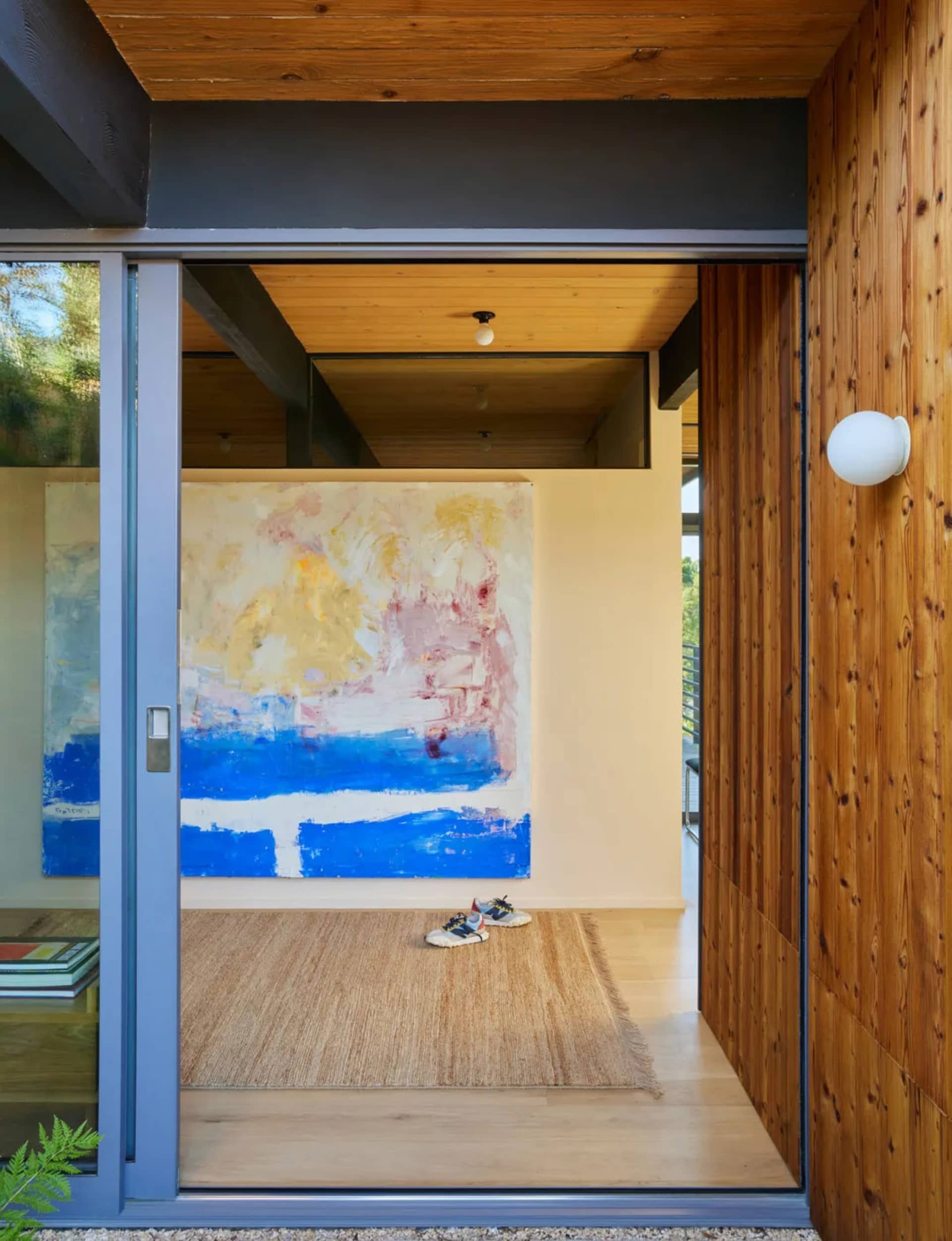 Cozy modern living space with a blue rug, a large painting, and comfortable seating options