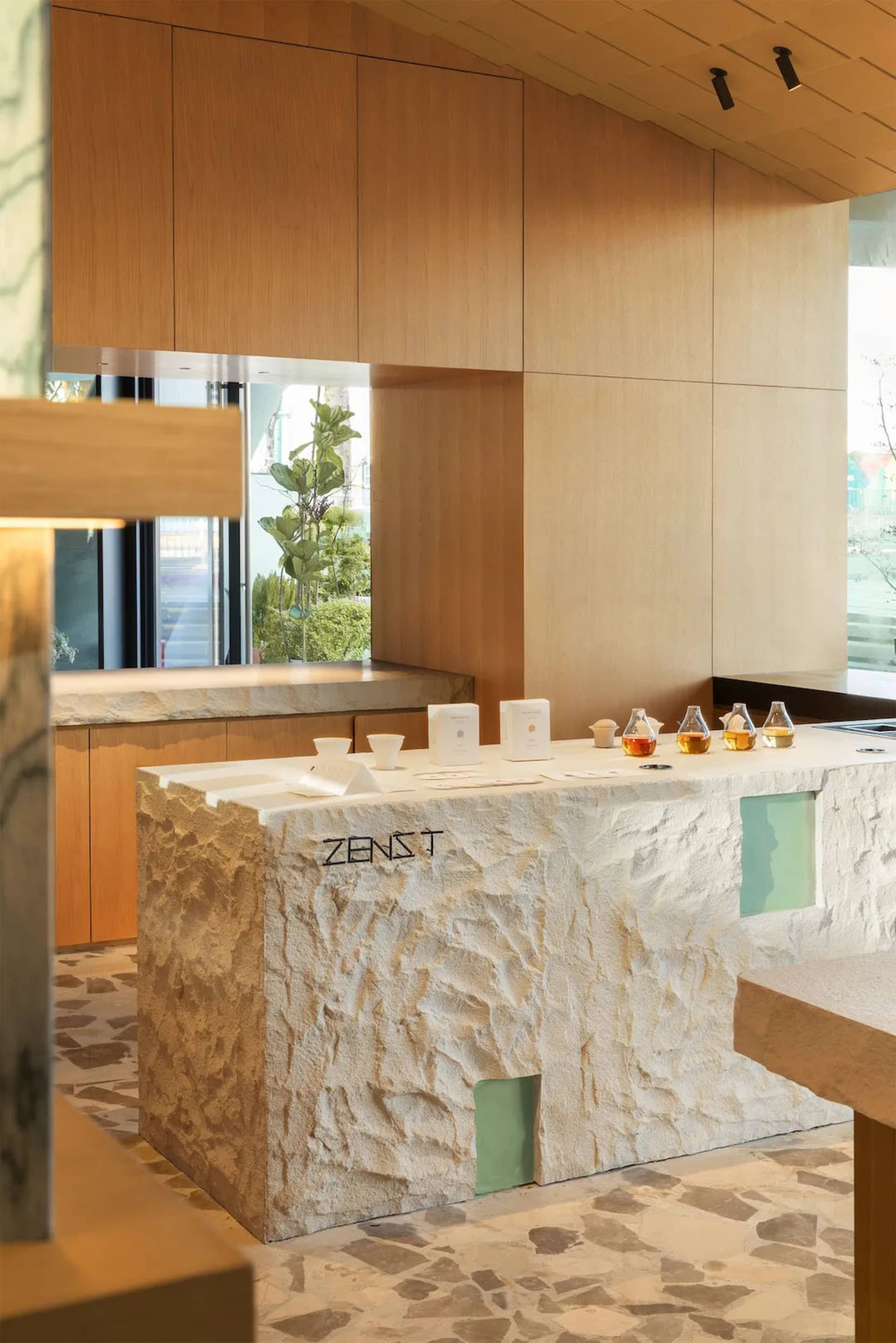 A modern kitchen or dining area with a marble counter, dim lighting, and several cups and bottles placed on the counter