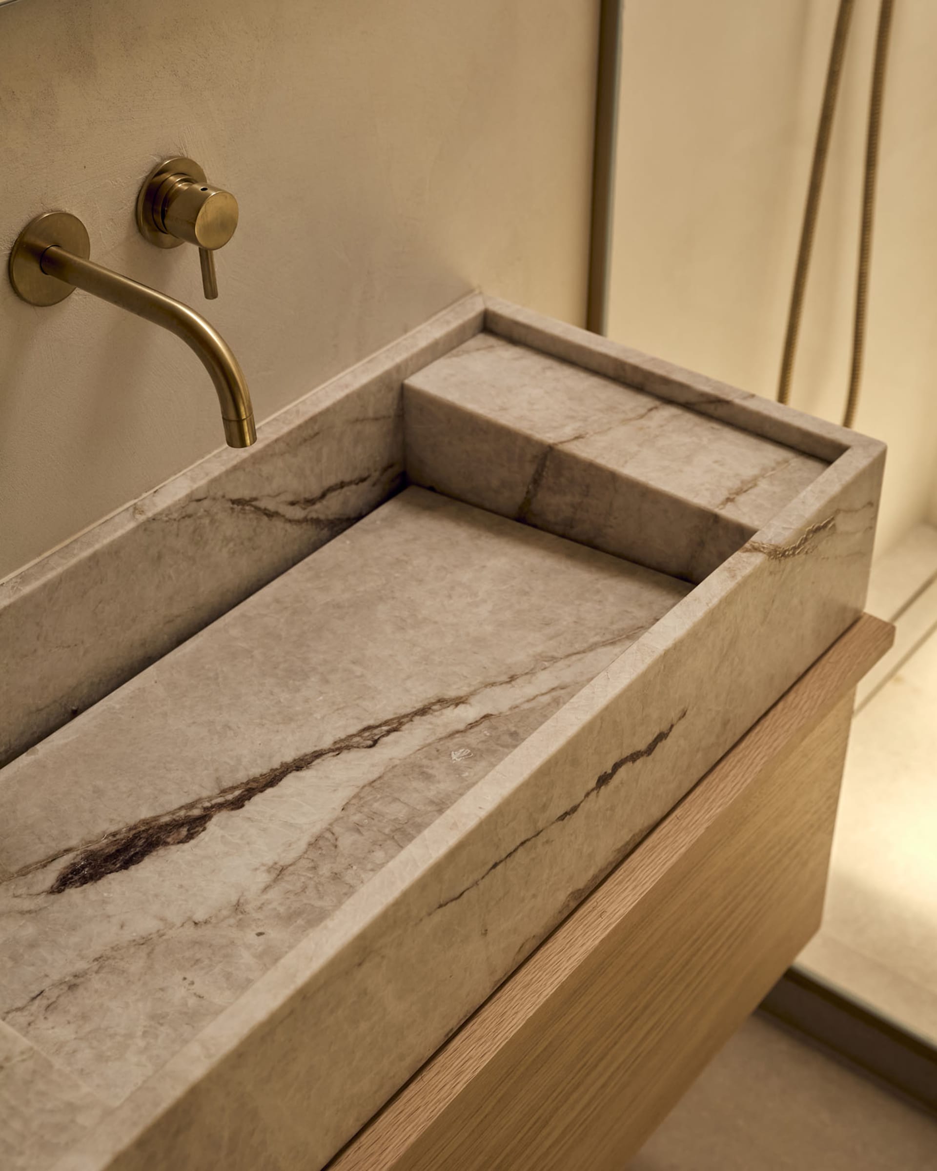 Bathroom with a marble countertop, metal sink, wooden cabinet, and wooden floor, lit with dim lighting