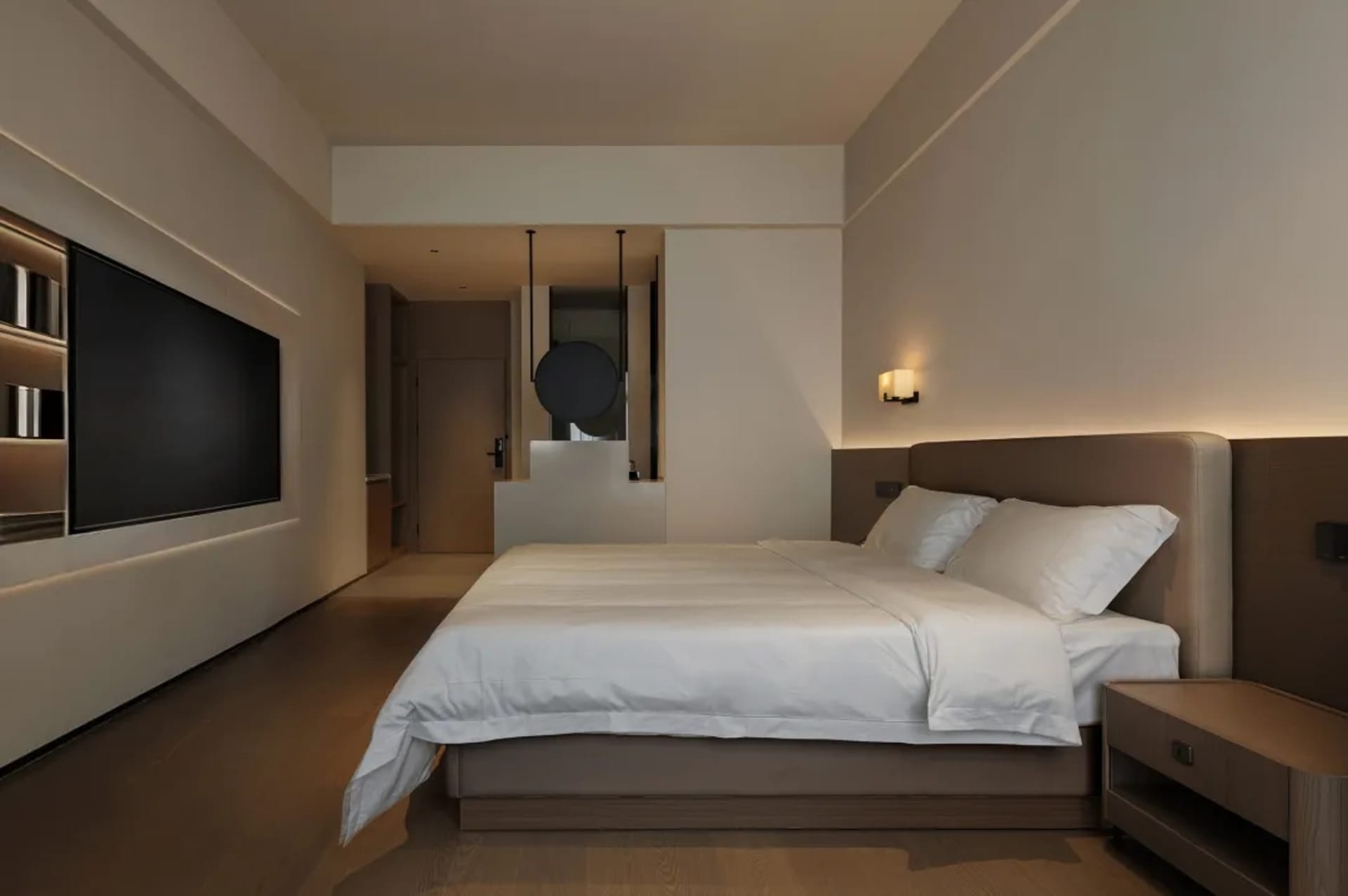A modern bedroom with a large bed, mounted TV, and mirror above the bed, set against a well-lit background