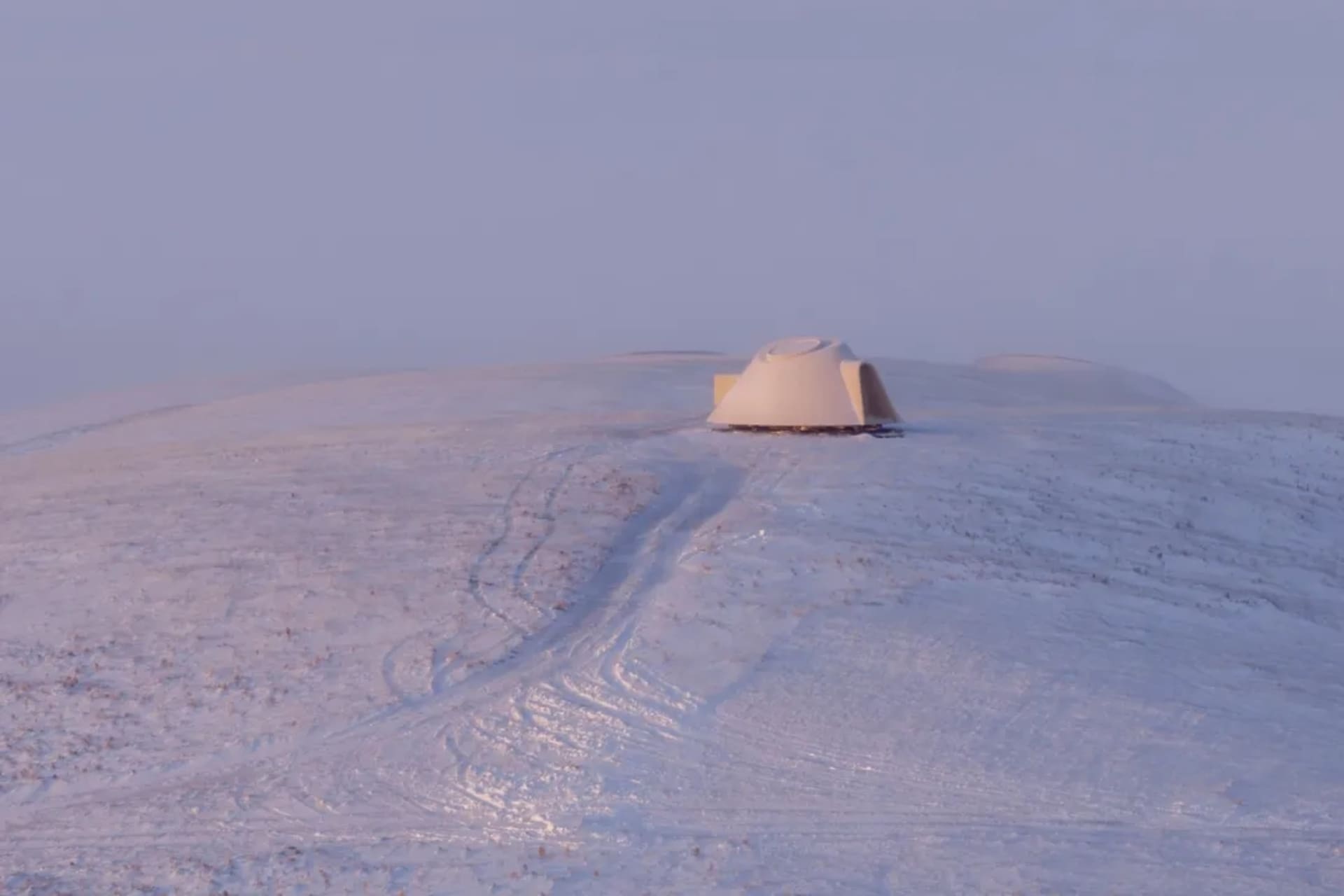 一片靜謐的雪景色中，半圓形的小屋突出在白色背景中