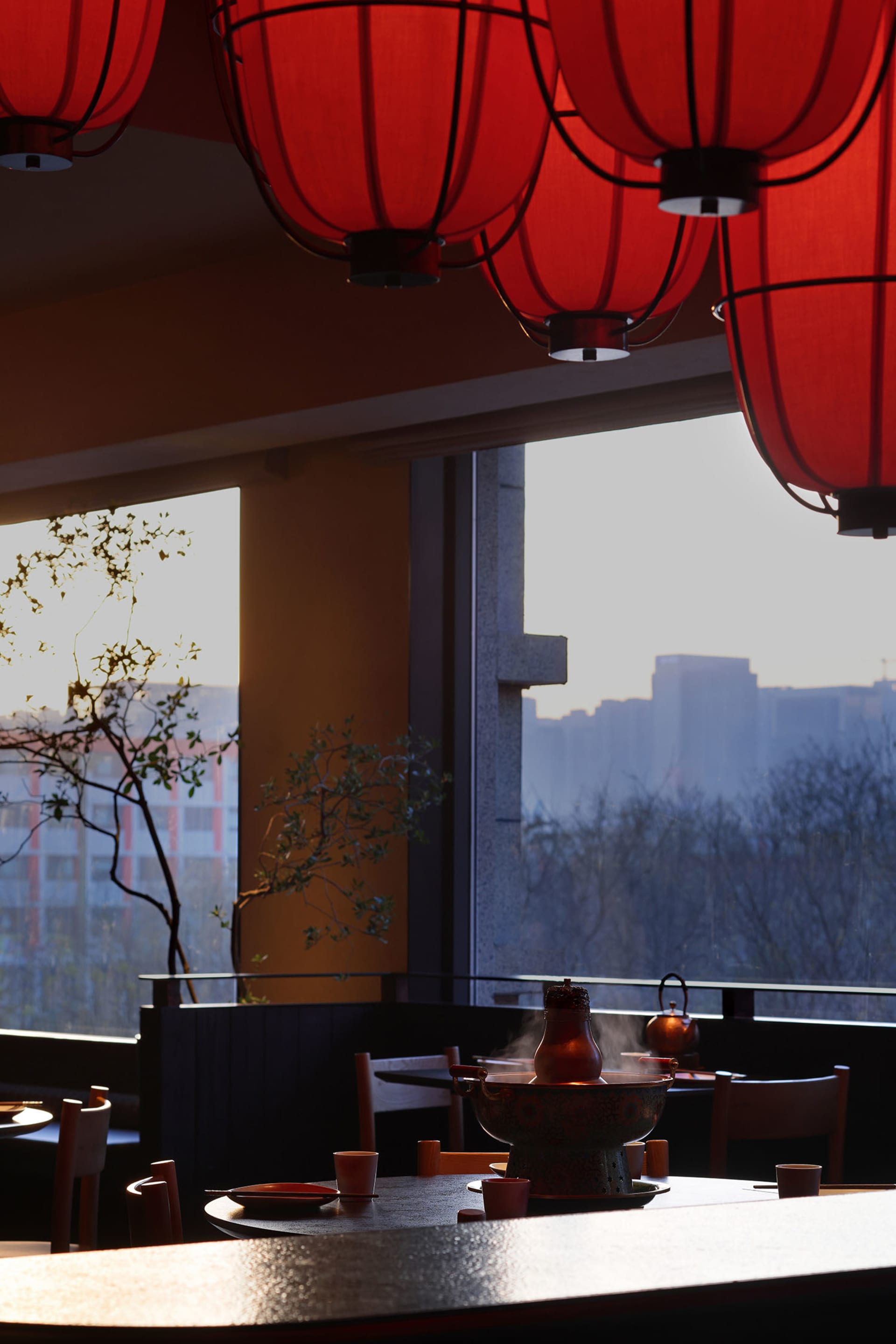 用餐區域配有餐桌椅、紅色點綴、碗與花瓶，置於自然光照的時尚餐廳中，暖色調的色彩