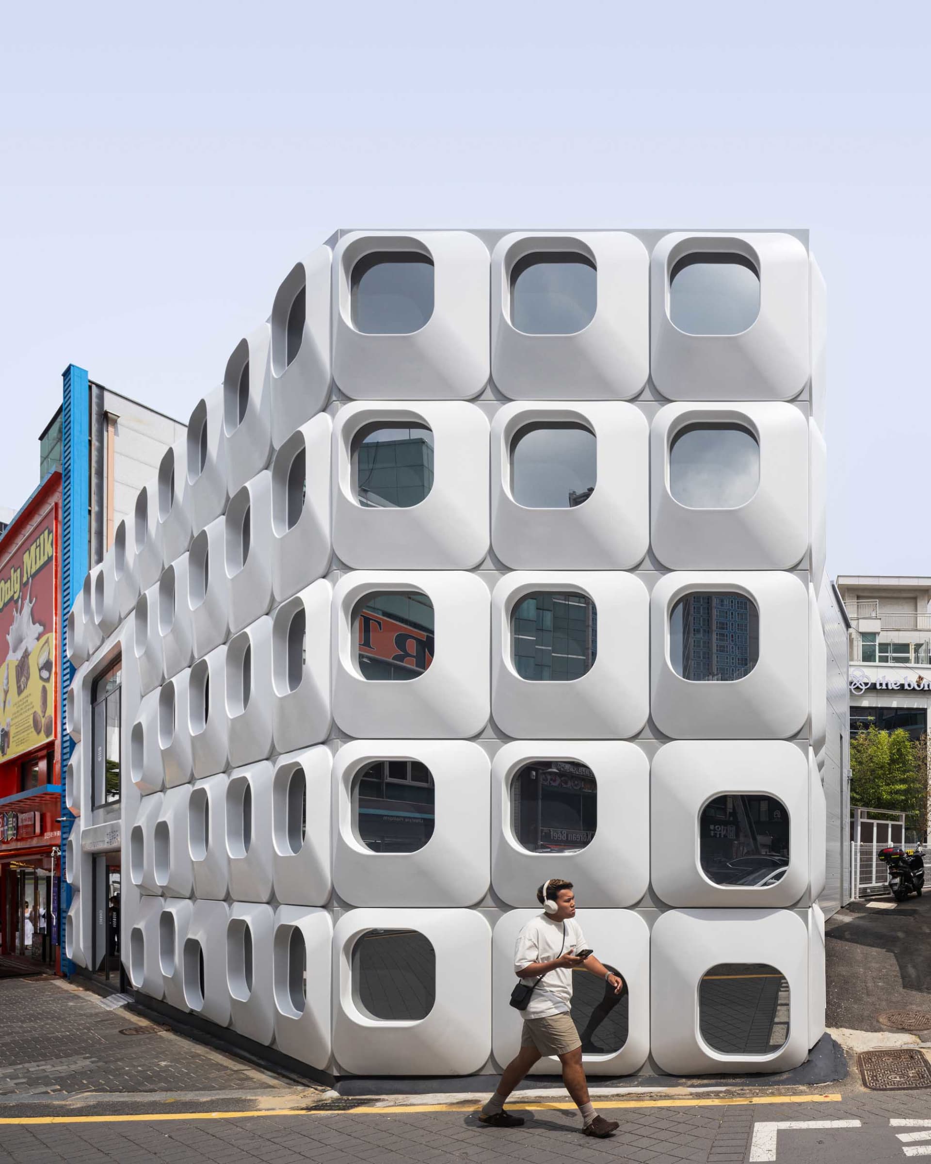 A large, white, modern office building with many square-shaped windows, bathed in natural light, creating a bright and inviting atmosphere