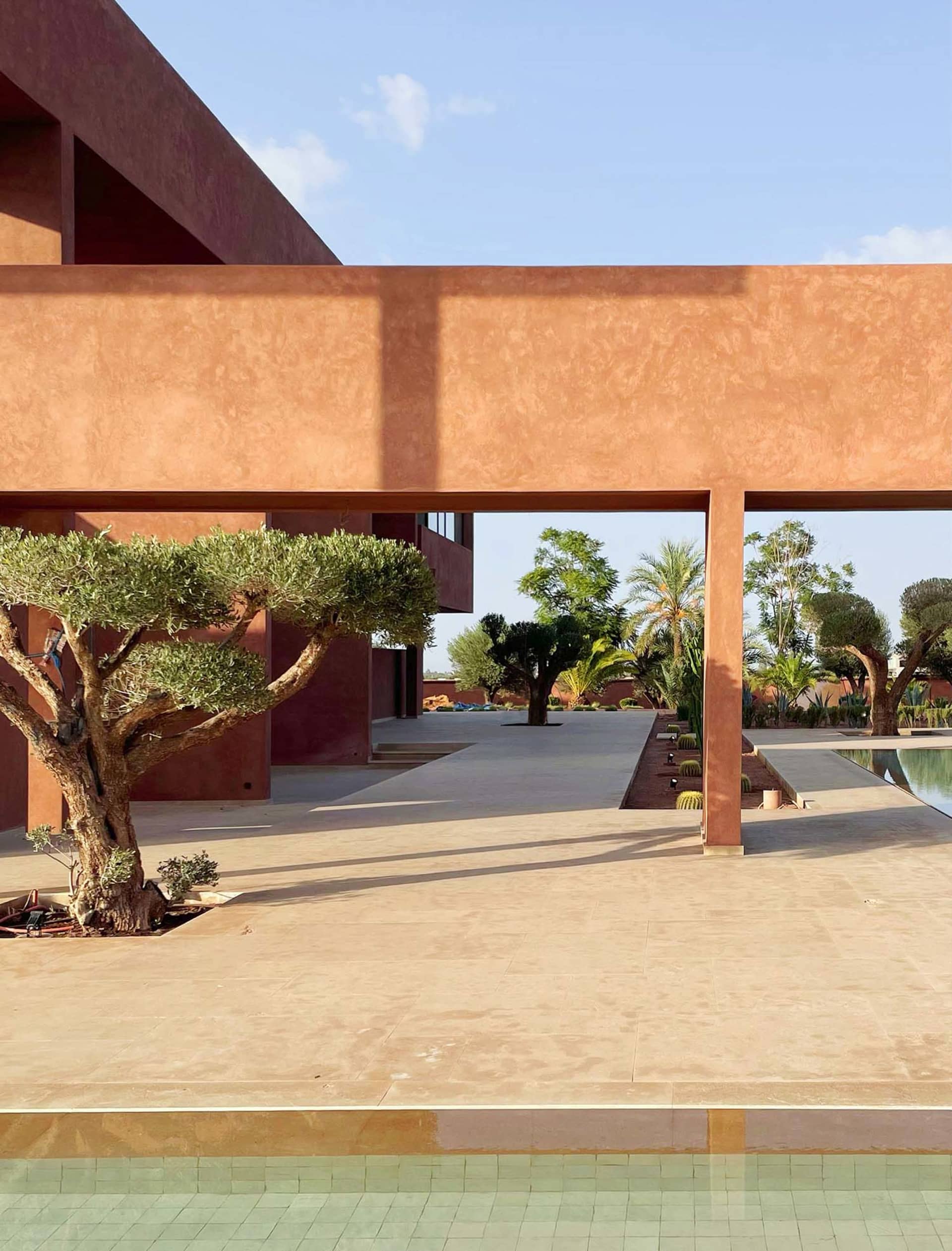 A residential outdoor area with a red building and a tree in the foreground, set against a warm and inviting background with a pool in the backyard