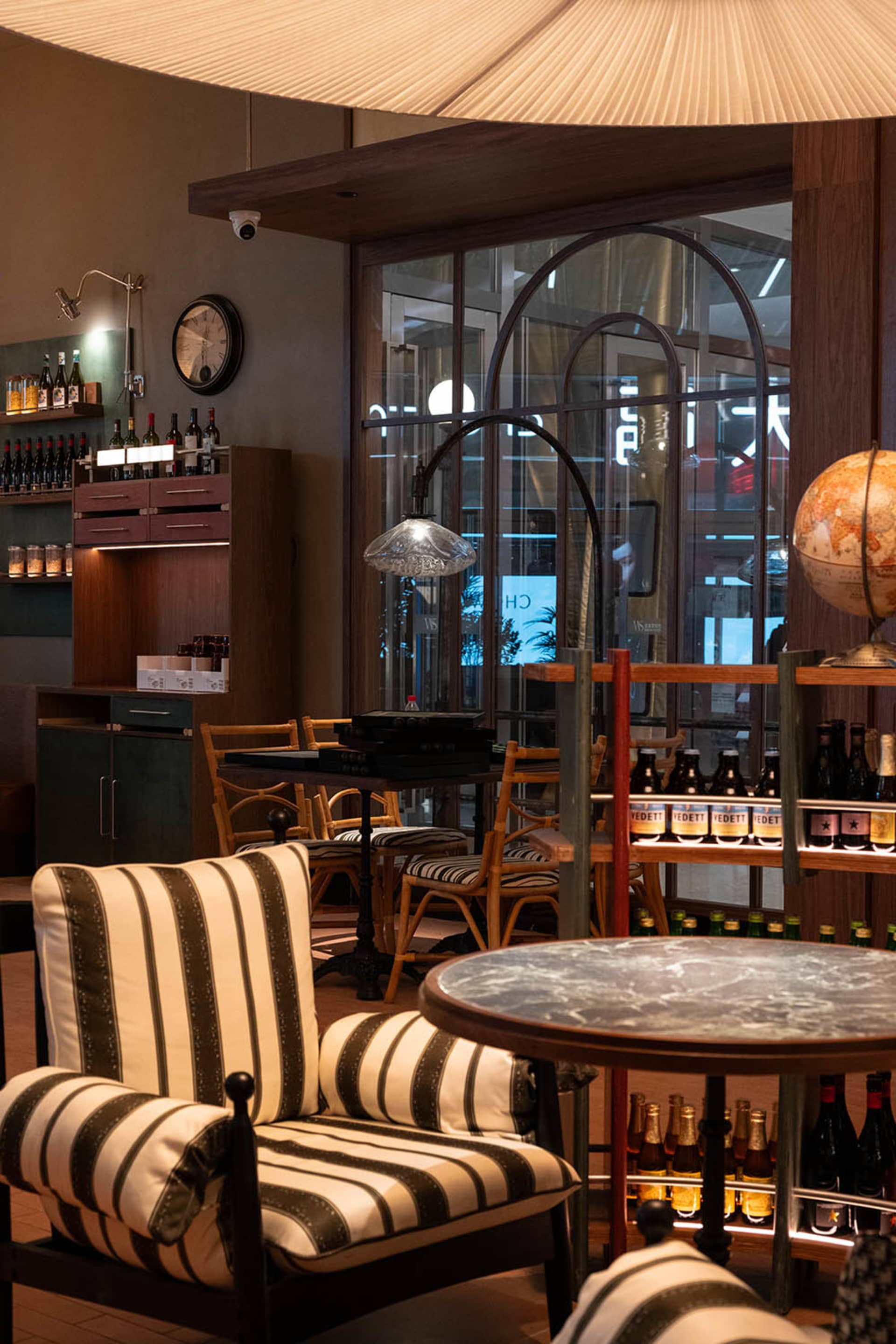 Cozy restaurant interior with a dining table, chairs, and a clock on the wall, featuring a mix of wood and metal elements and soft warm lighting