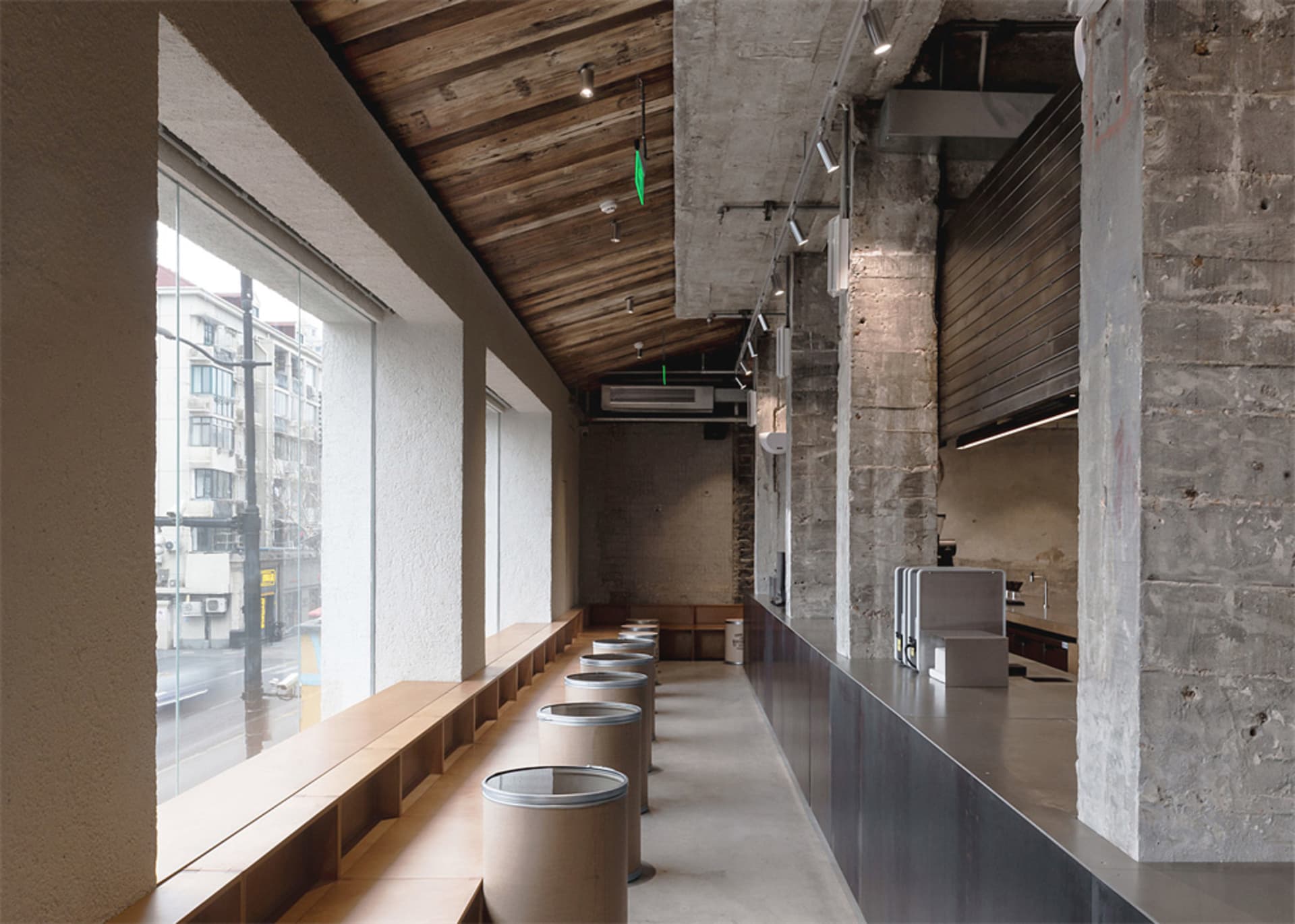 A spacious dining room with a high ceiling, wooden floor, and tables and chairs, lit by dim overhead lighting
