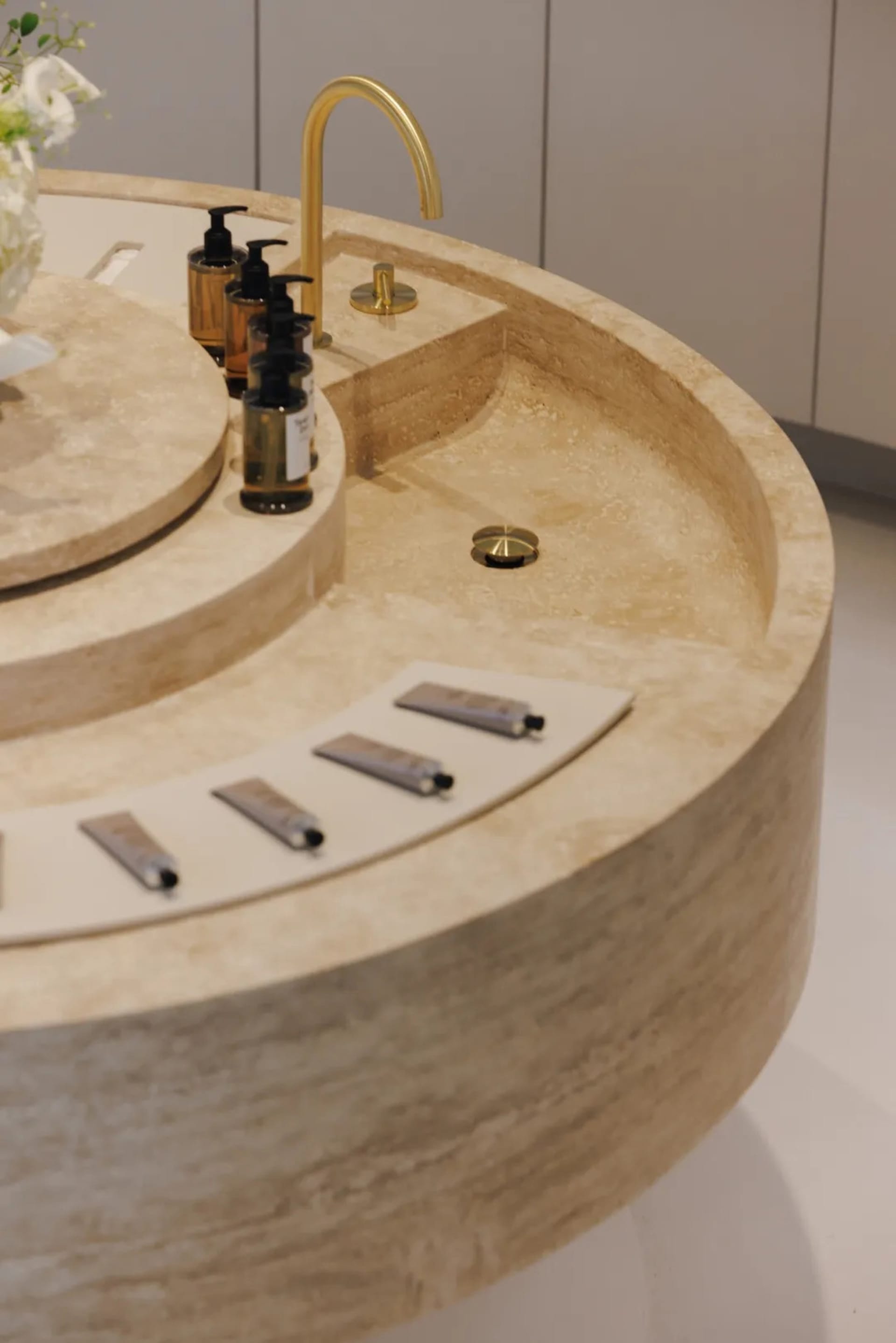 Modern bathroom with a marble counter featuring a sink, a vase, and several bottles in a modern and elegant style