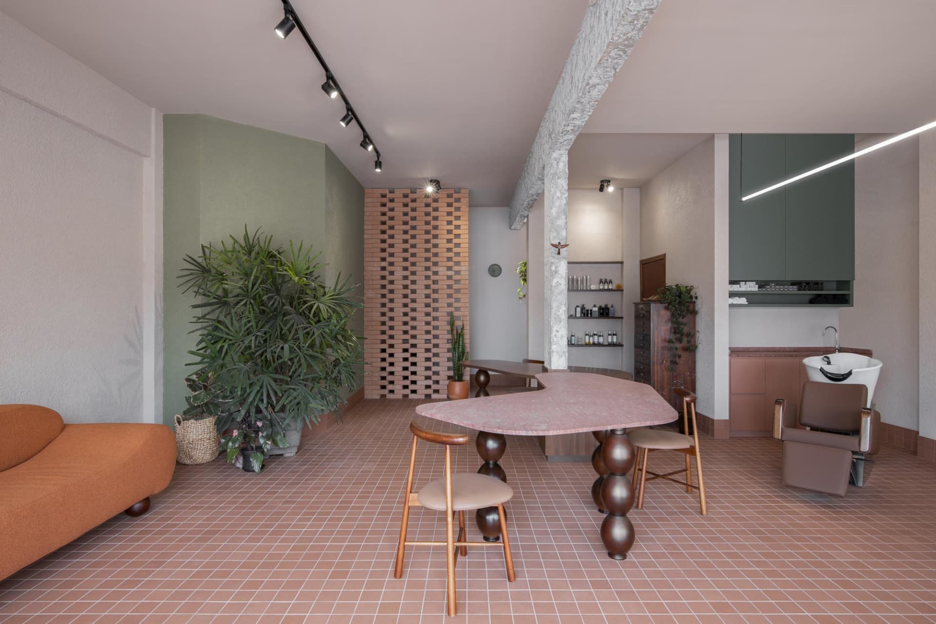 A modern restaurant with a large dining table, potted plants, and soft warm lighting creating a welcoming atmosphere