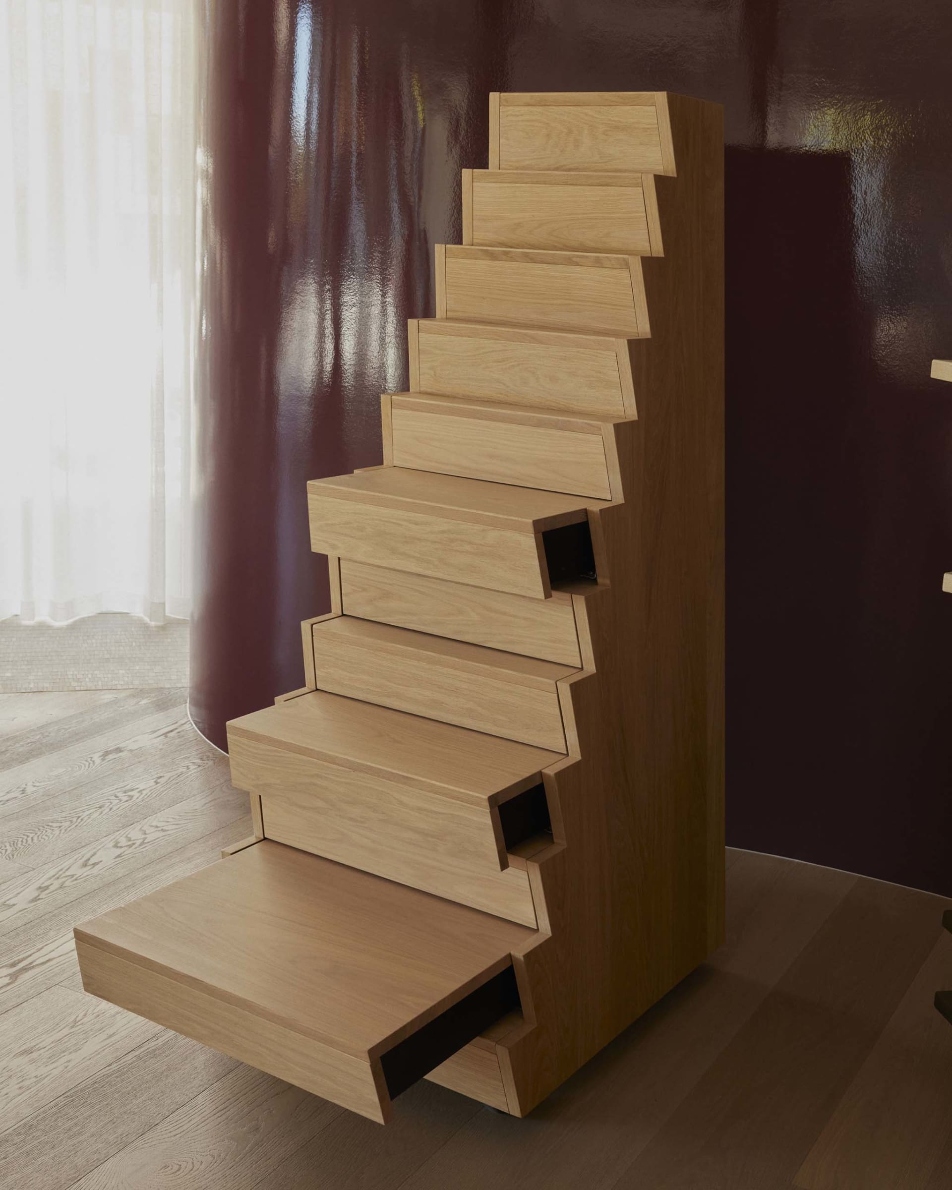 Wooden staircase with a red wall, natural light, and a warm inviting atmosphere