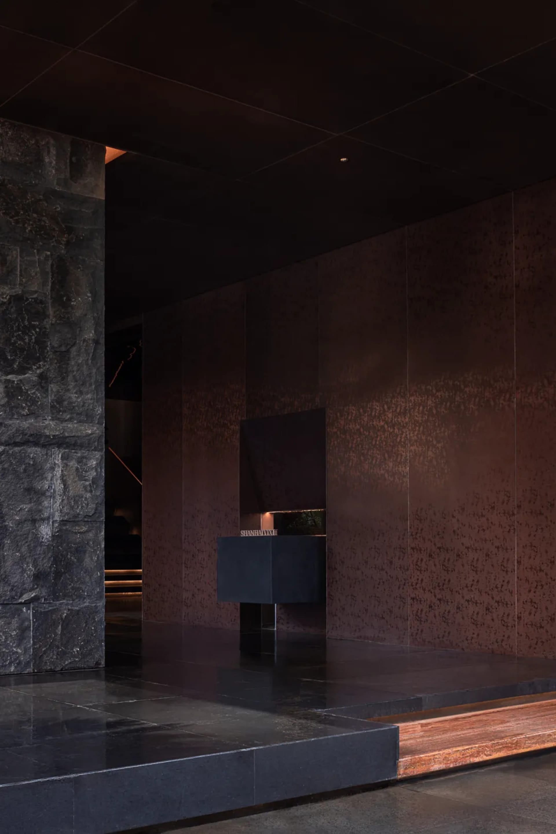 Bathroom with a black marble countertop, sink, and mirror in a modern space with dim lighting