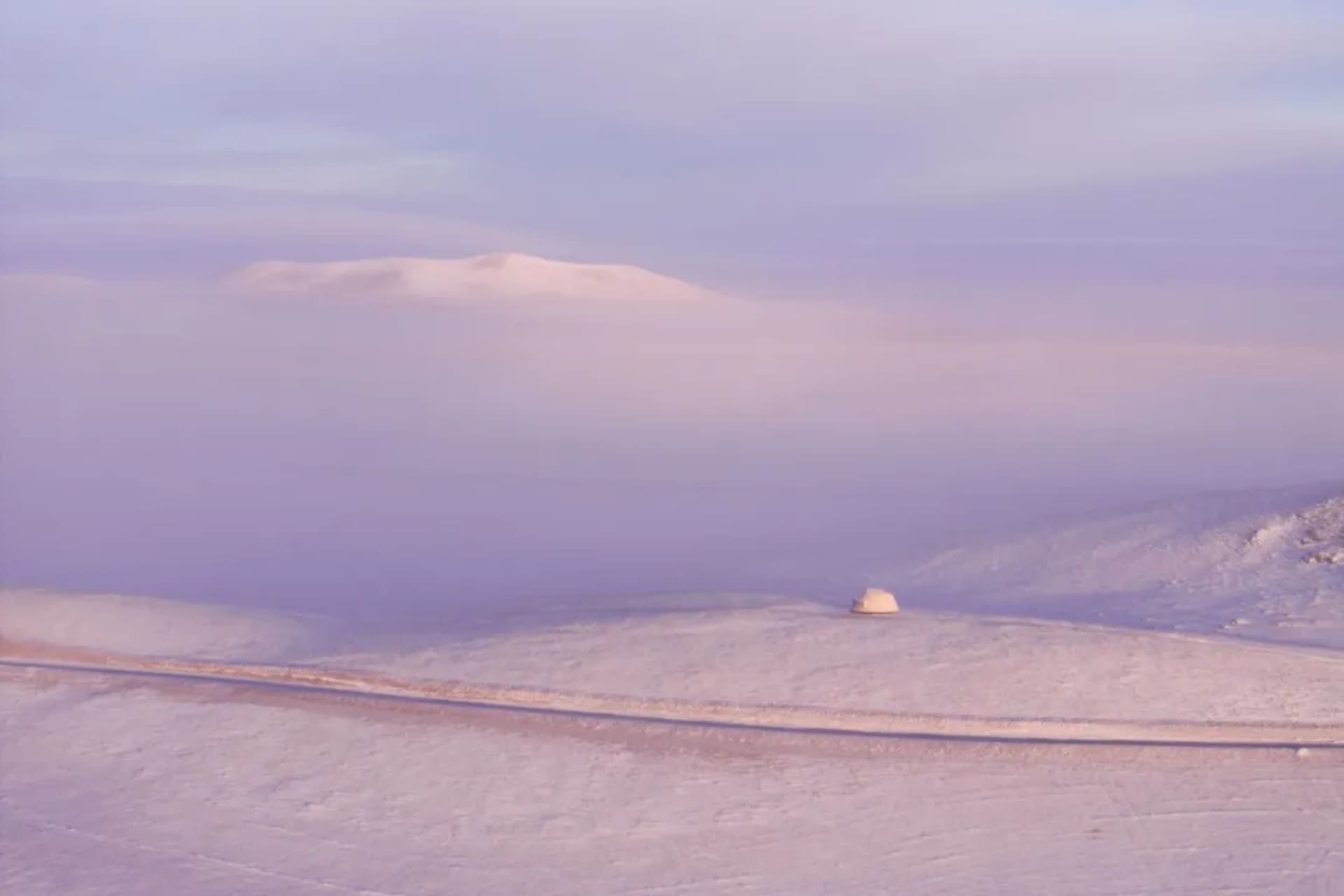 靜靜的雪景景色裡面有個原始木頭的山屋在前景，周圍被覆蓋著雪的山坡