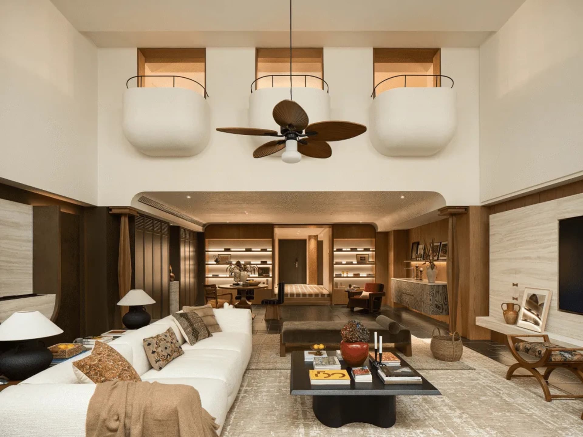 A well-lit living room with a white couch, a chair, and a dining table, featuring a large ceiling fan and a chandelier, with natural light coming in through the windows, creating a warm and cozy atmosphere