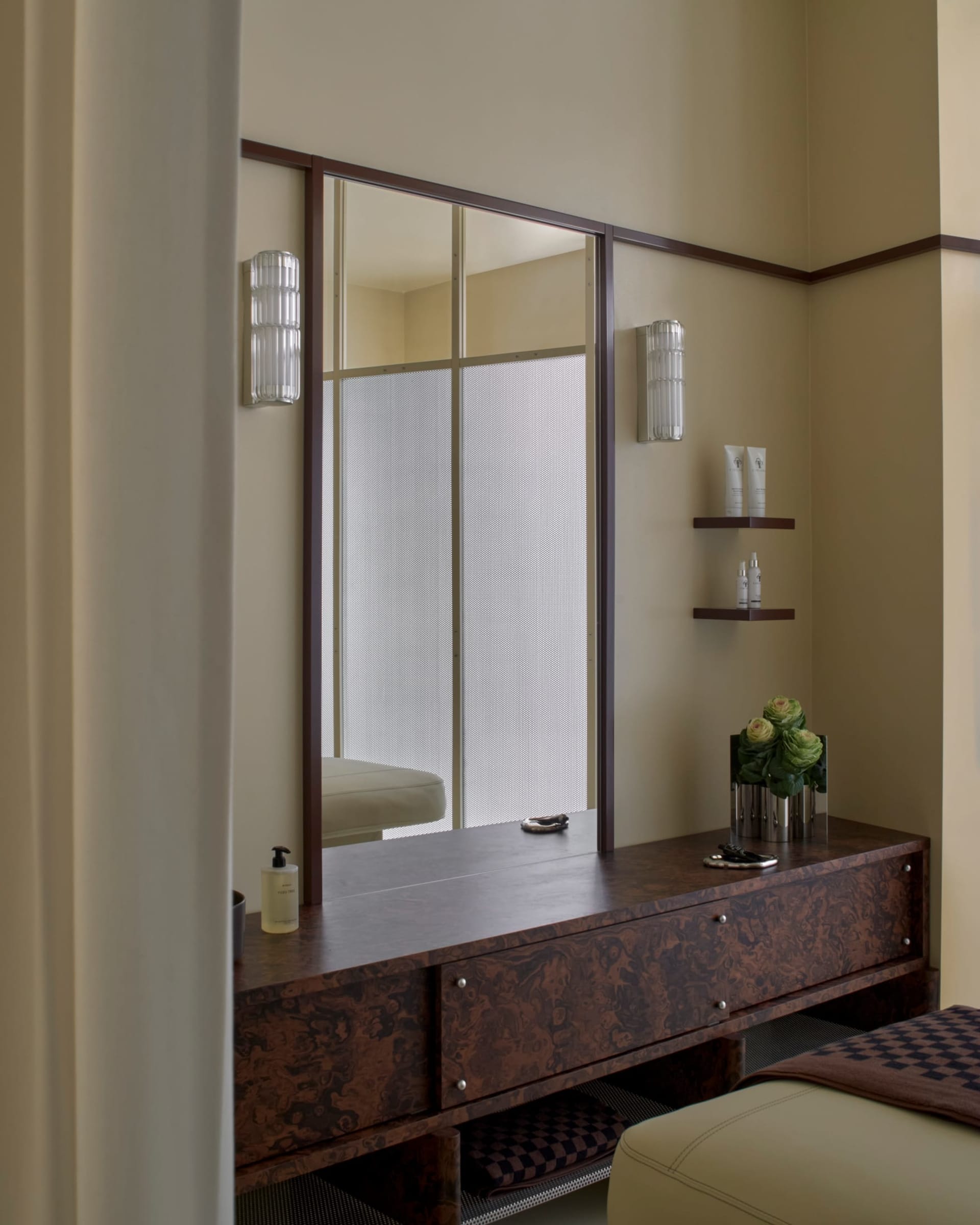 Bathroom with a wooden vanity, sink, and vase with flowers, featuring a warm and inviting atmosphere with wood and glass materials