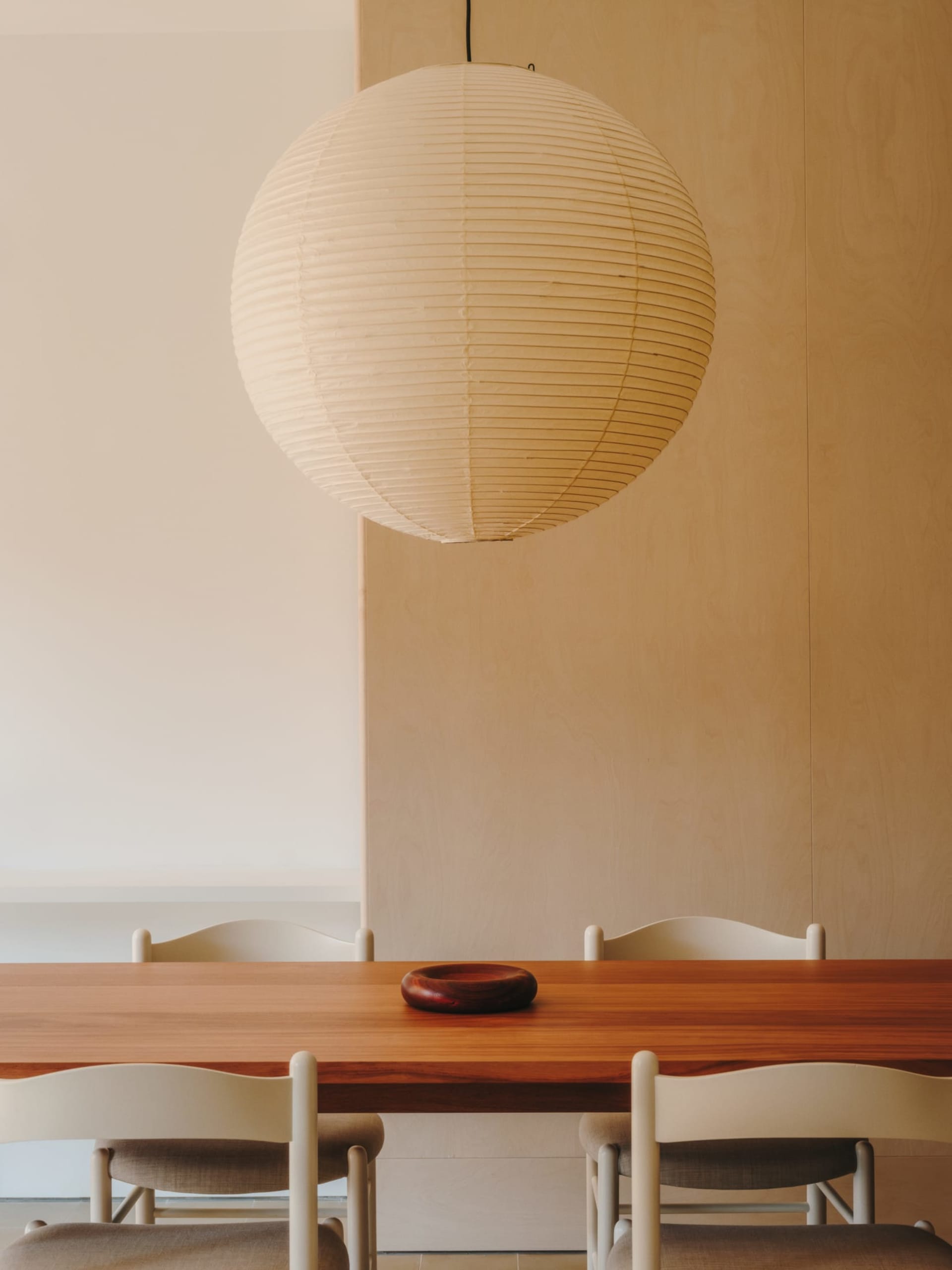 Dining room with a wooden table and chairs, well-lit and inviting, with a bowl on the table