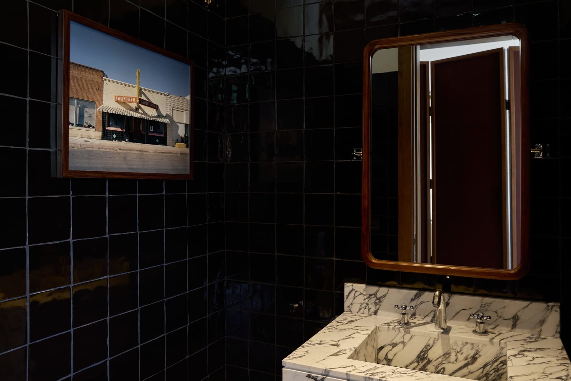 Bathroom with a white sink and brown mirror, set against a black and white tile floor