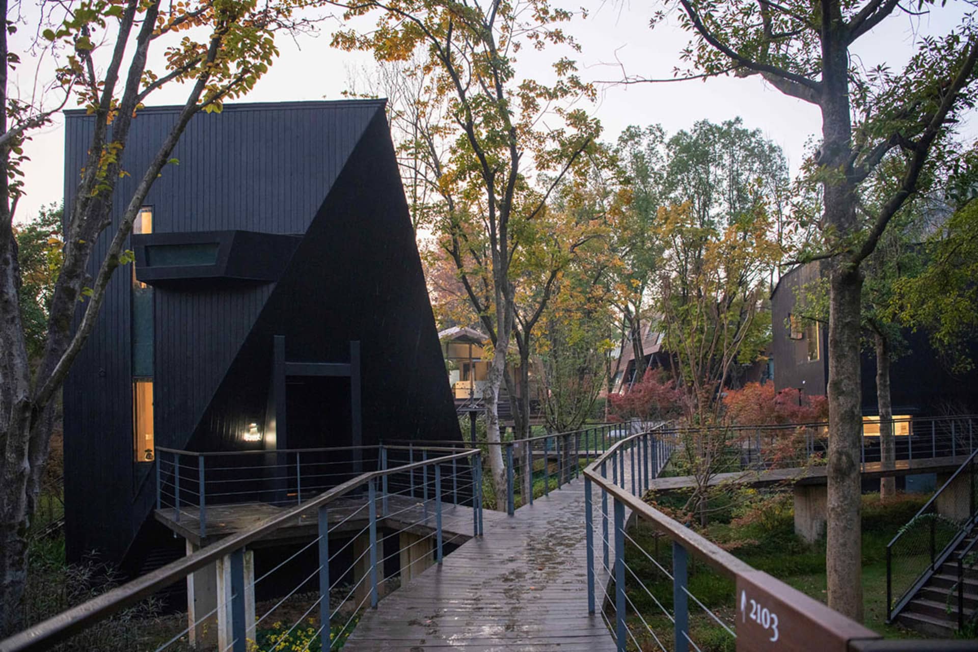 A black house with a triangle-shaped structure surrounded by trees, creating a serene atmosphere