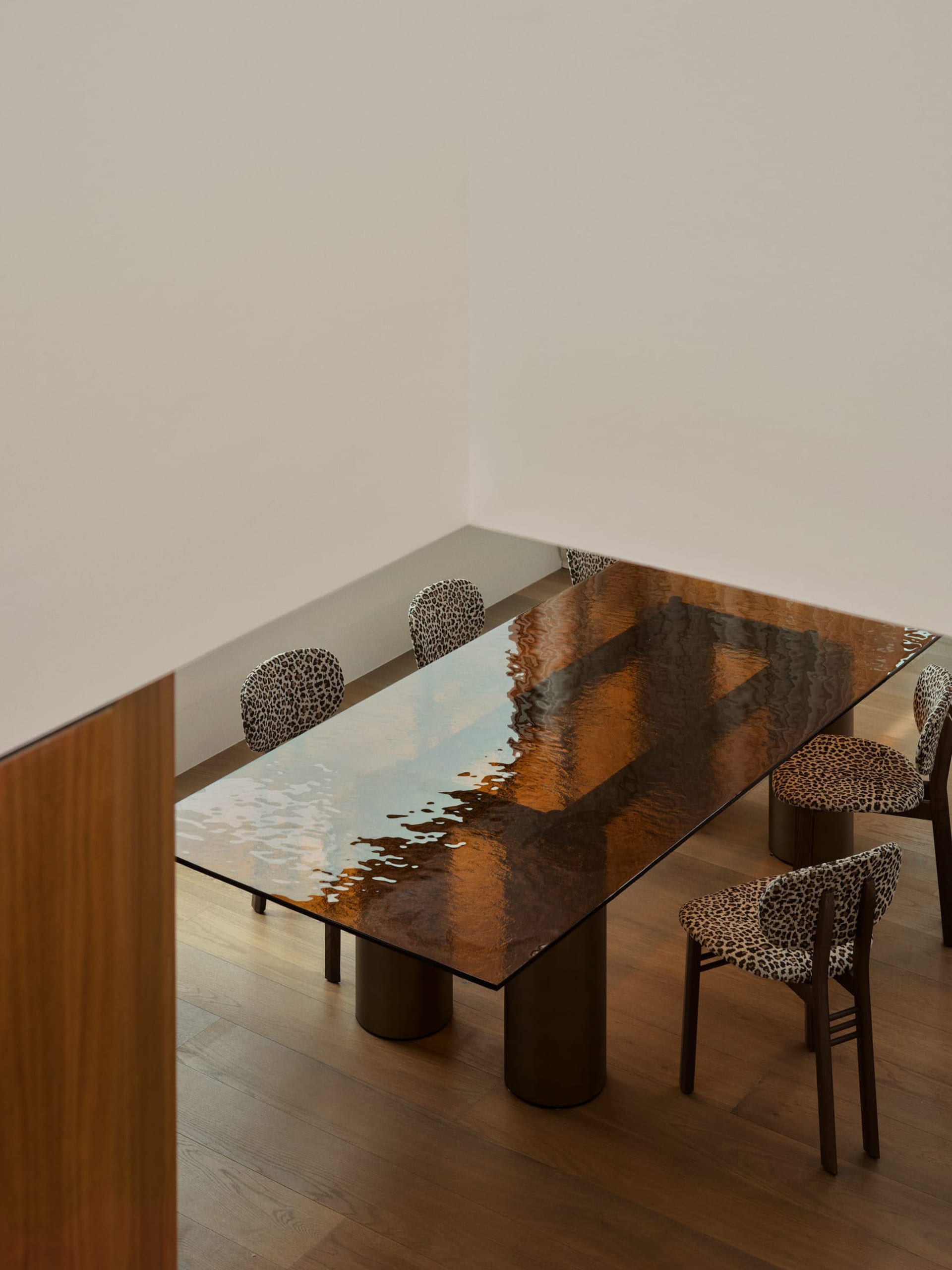 Dining room with a wooden table and leopard print tablecloth, surrounded by chairs in a well-lit space with natural light