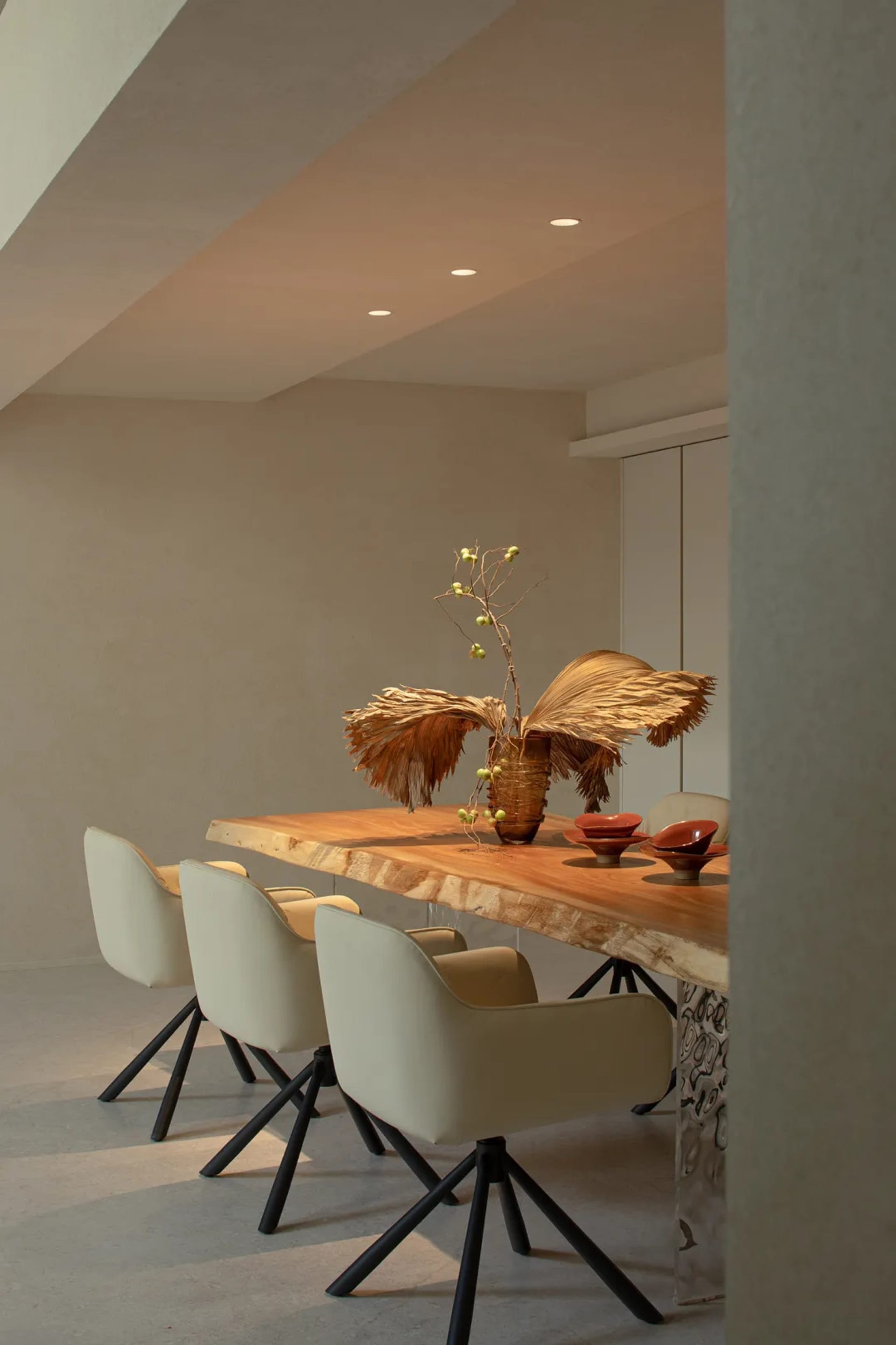 Dining room with a wooden table and chairs, a large window, and a vase, featuring a modern style with a focus on functionality and simplicity
