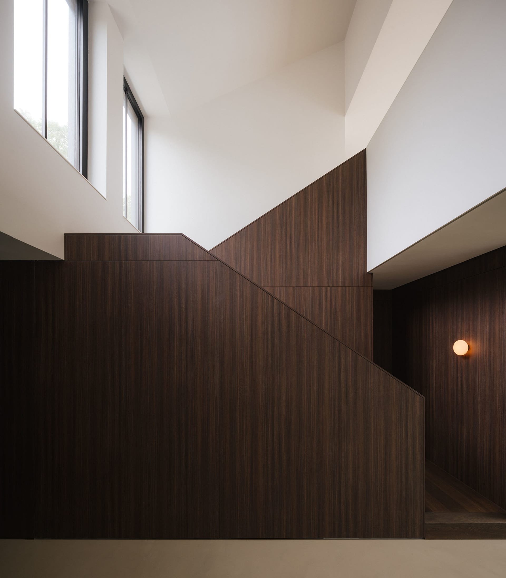 A wooden staircase with a wooden banister in a dark room near a window