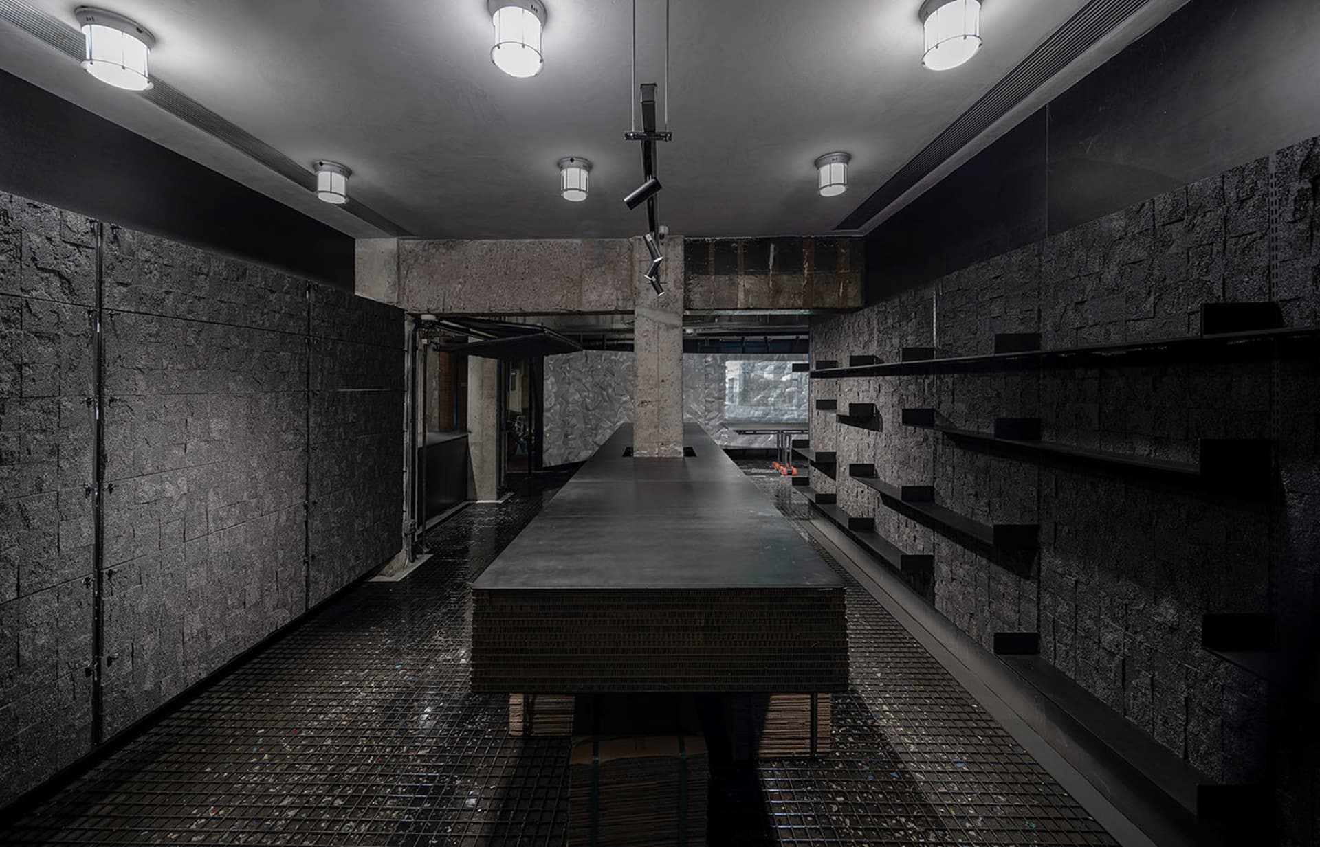 Modern kitchen with a dark countertop, a large window, and a dining table, featuring a sink and refrigerator, with dim lighting creating a cozy atmosphere