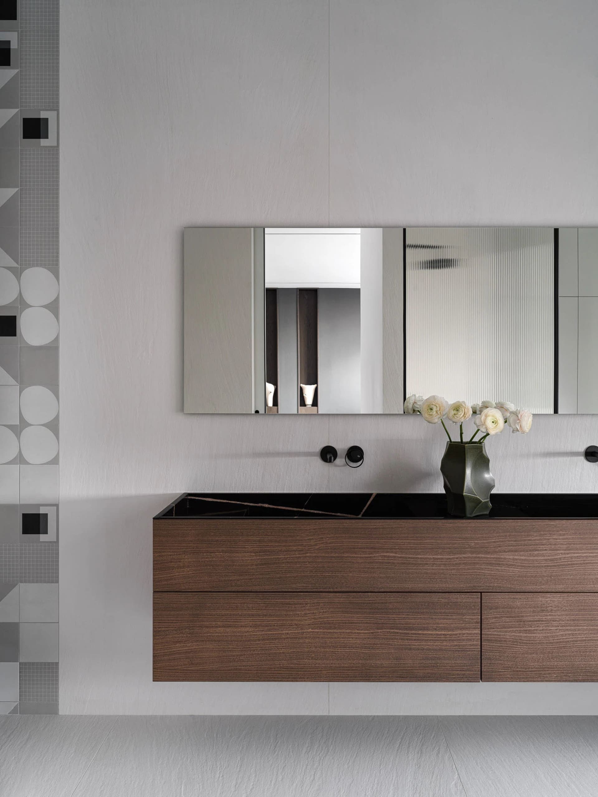 Bathroom with a sink, mirror, and a vase with flowers, well-lit and elegant