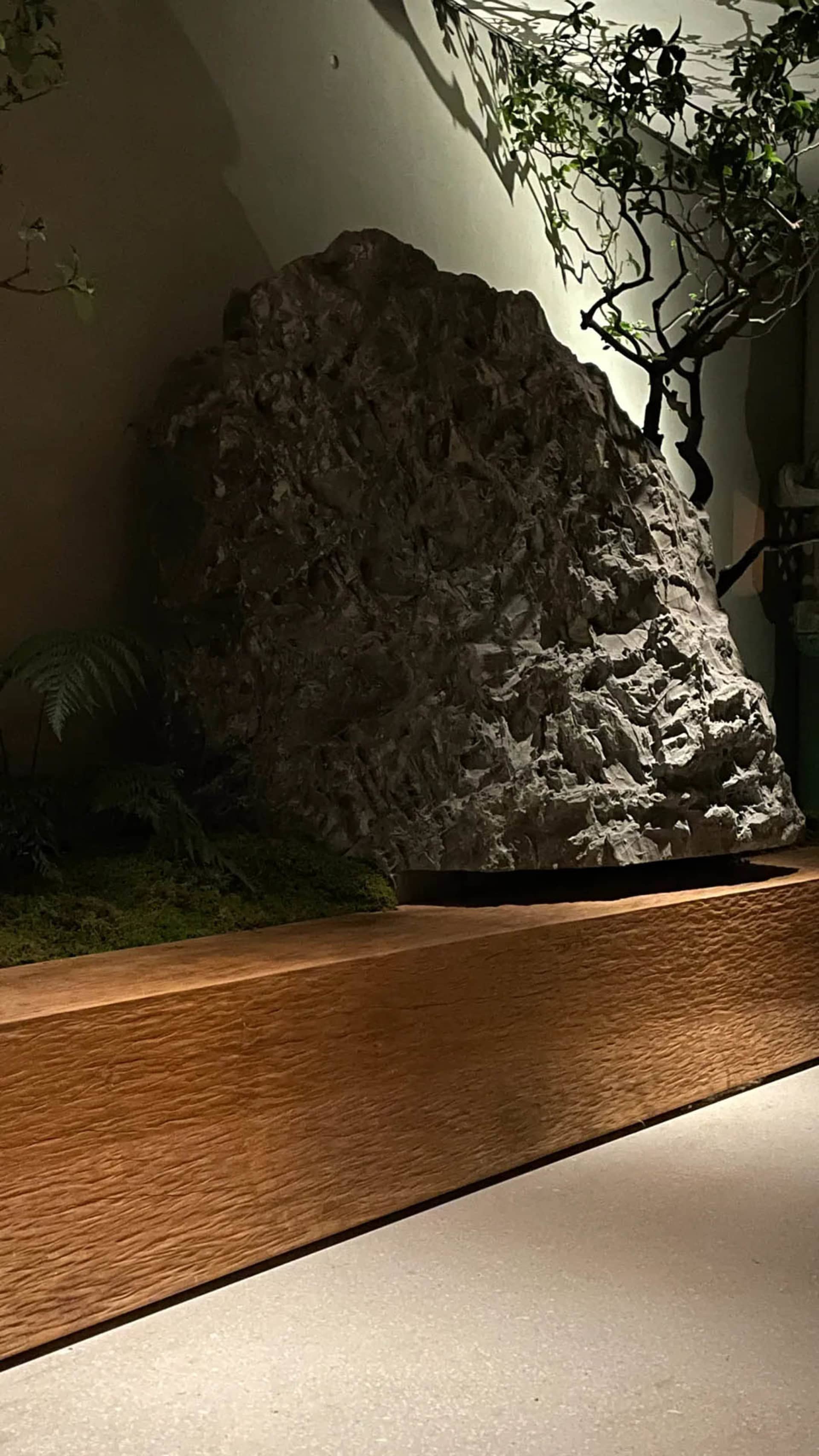 一間黑暗的房間內有個大灰色岩石在前景，背景有一個較小的灰色岩石，使用劇烈的光源燈光效果