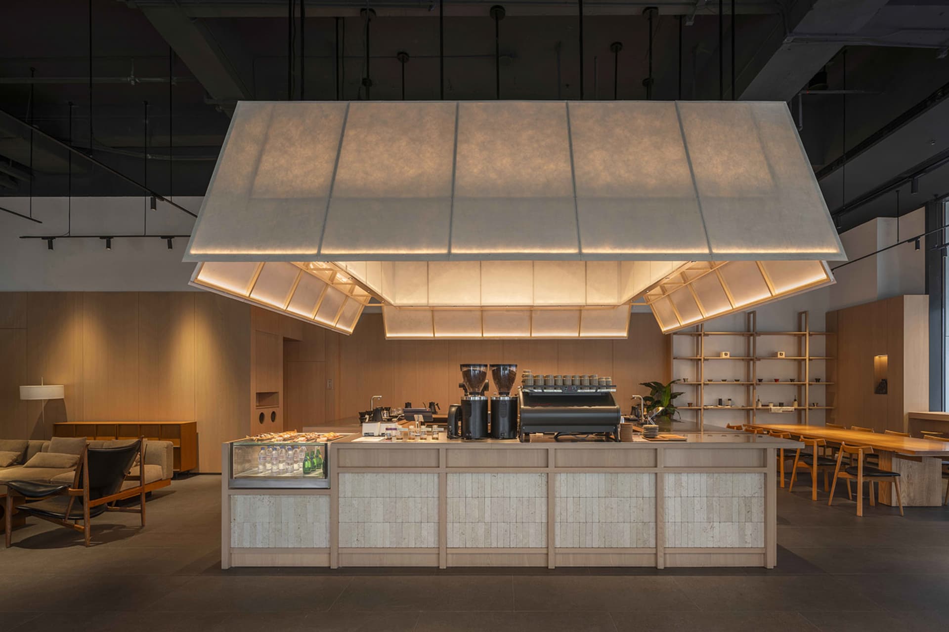 Warm and inviting cafe interior with a wooden counter, soft lighting, and a variety of cups and bottles on display