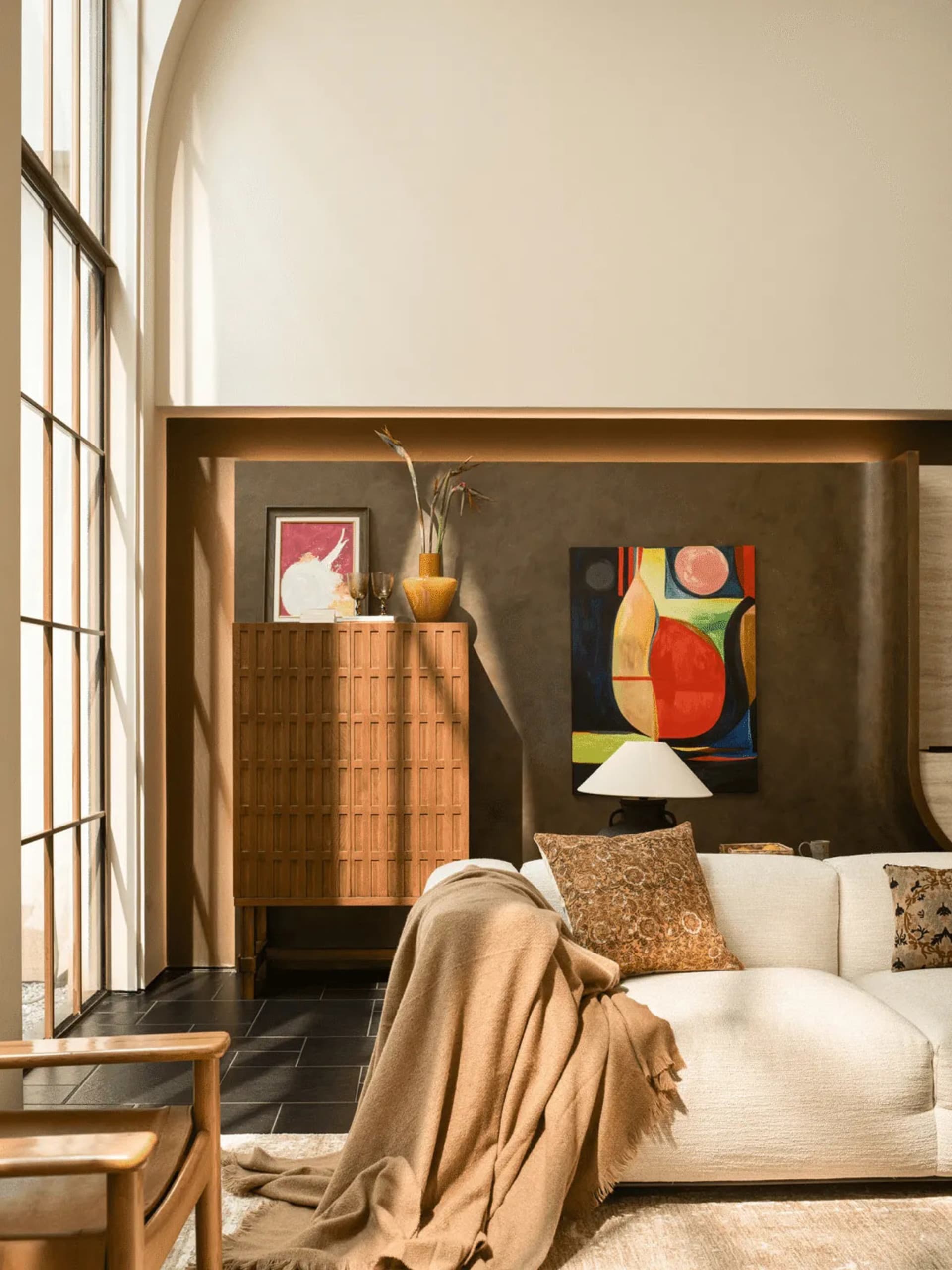 A modern living room with a white couch, a chair, and a potted plant, well-lit and welcoming