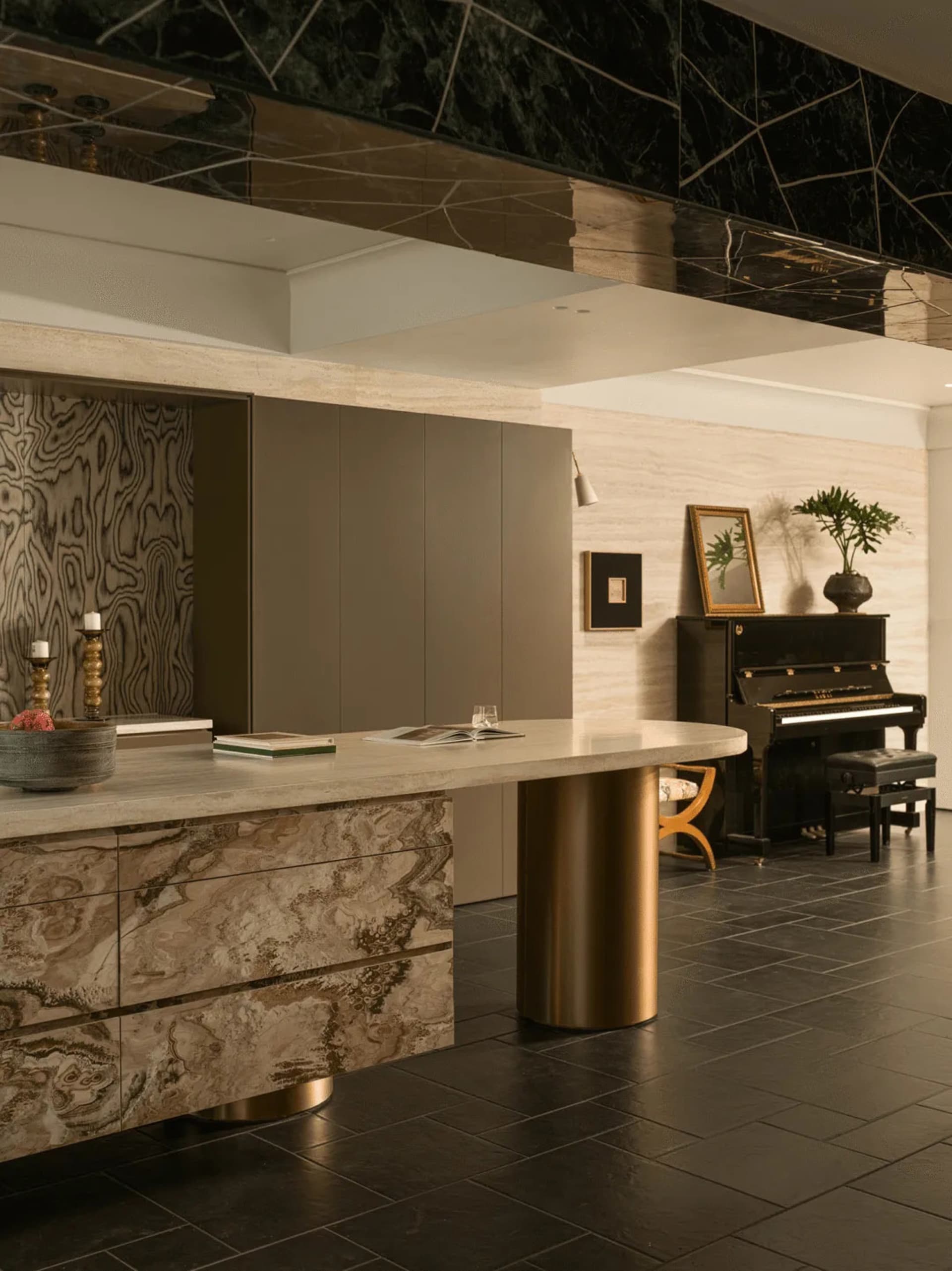 Photograph of a modern living room with a black and gold color scheme, featuring a piano, dining table, and counter, with a focus on luxury and sophistication