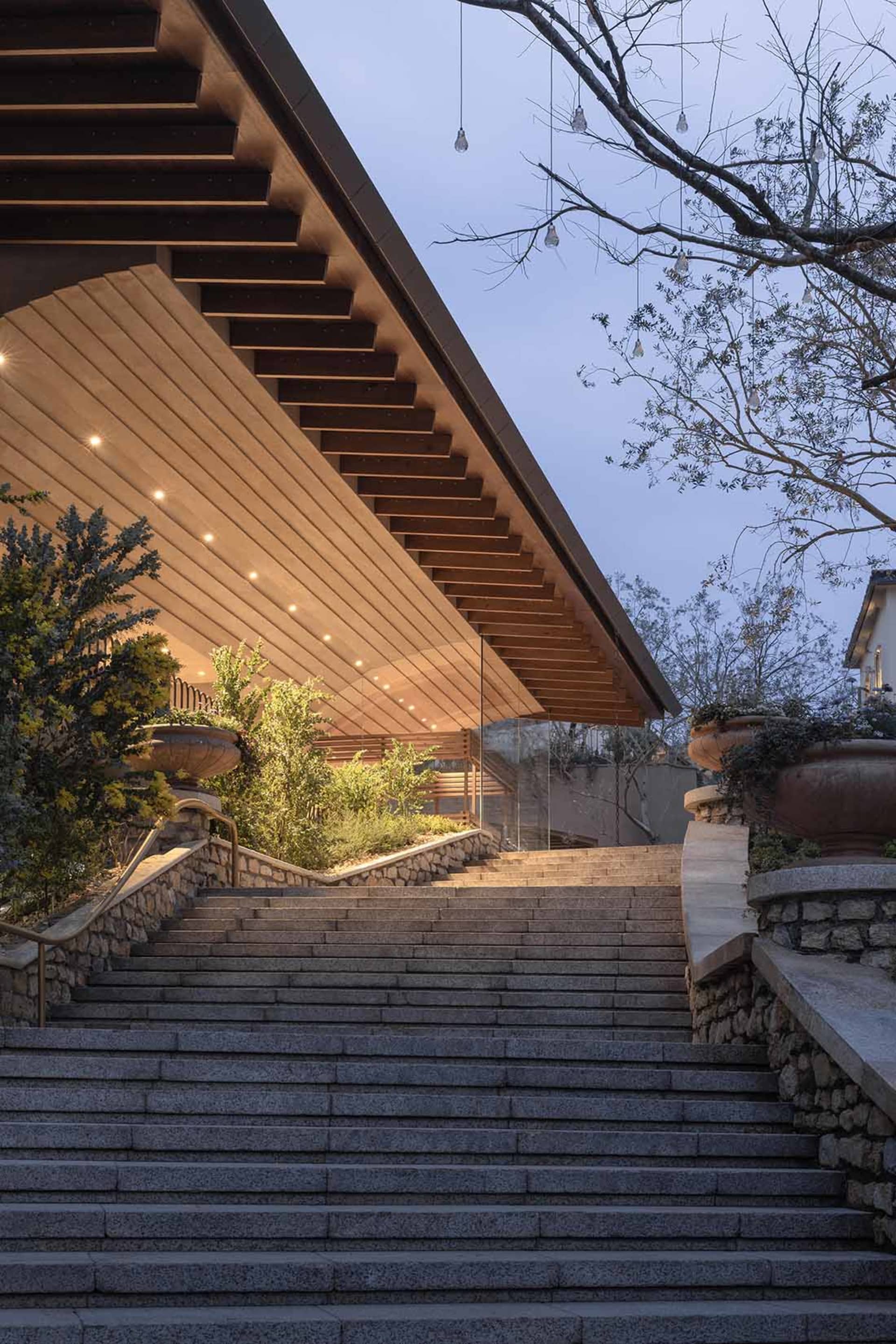 A modern building with a stone staircase leading up to a wooden door, set against a dimly lit background