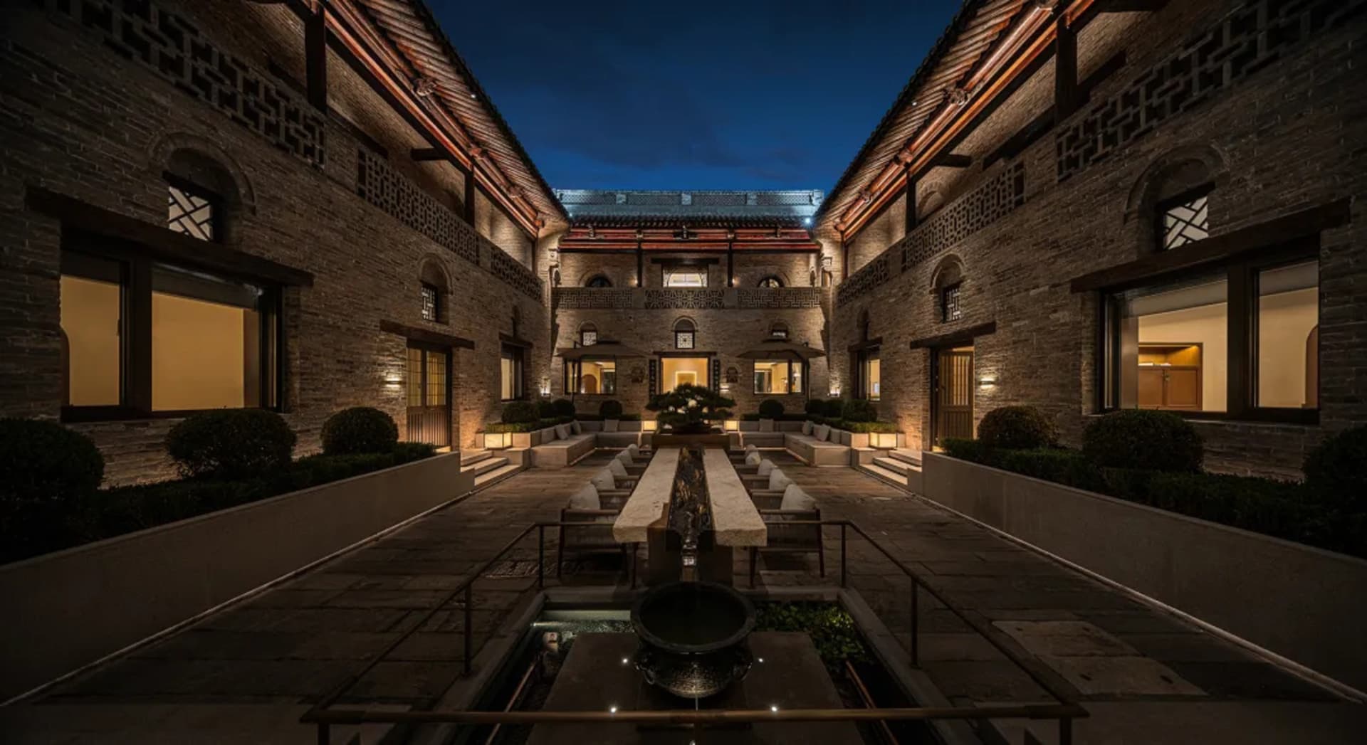 一座大型明亮的建築物，庭院，石頭，木材，水池，融合了傳統和現代元素的建築