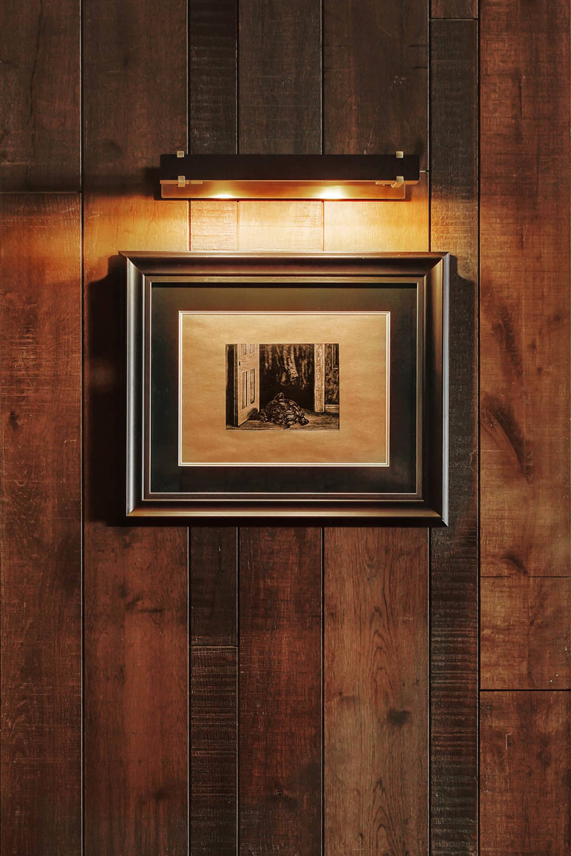 A dimly lit living room with a wooden floor, a couch in the center, and a chair to the right, creating a warm and intimate atmosphere