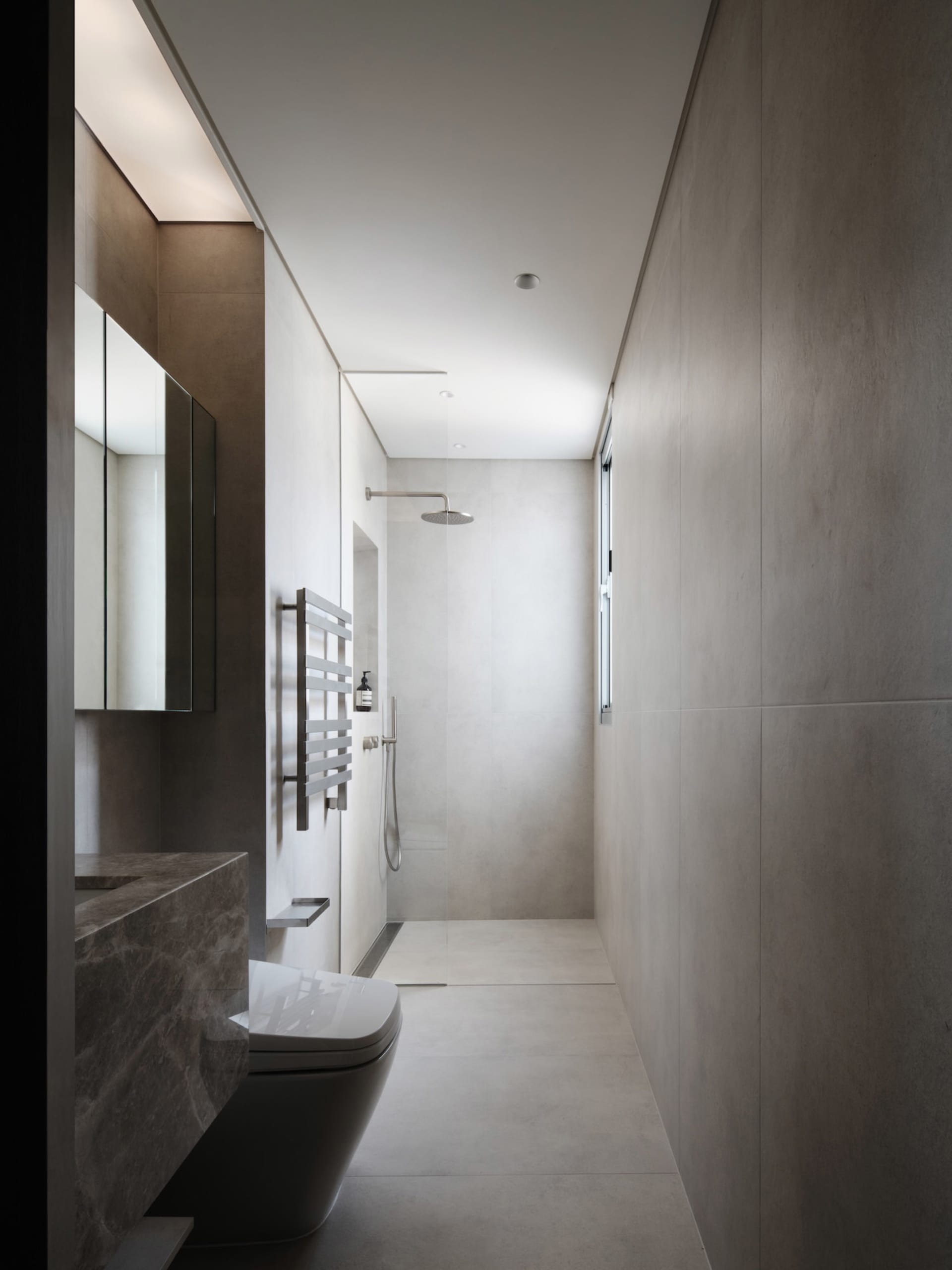 A modern bathroom with a white toilet and sink, a large mirror above the sink, and natural light from a window