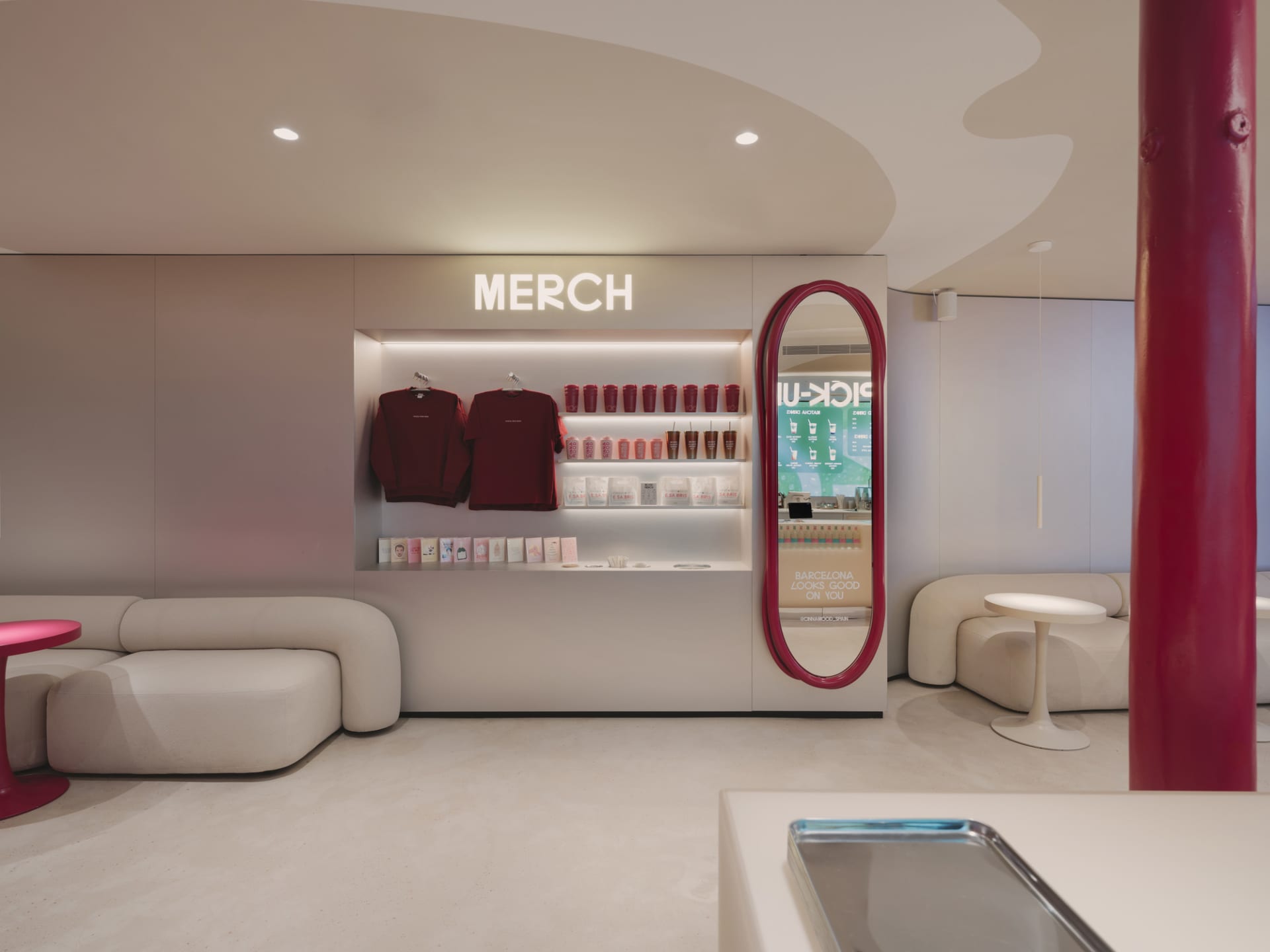 一間穿著現代風格的商店，白色主調，牆上掛著一面大鏡，展示著整齊排列的上衣