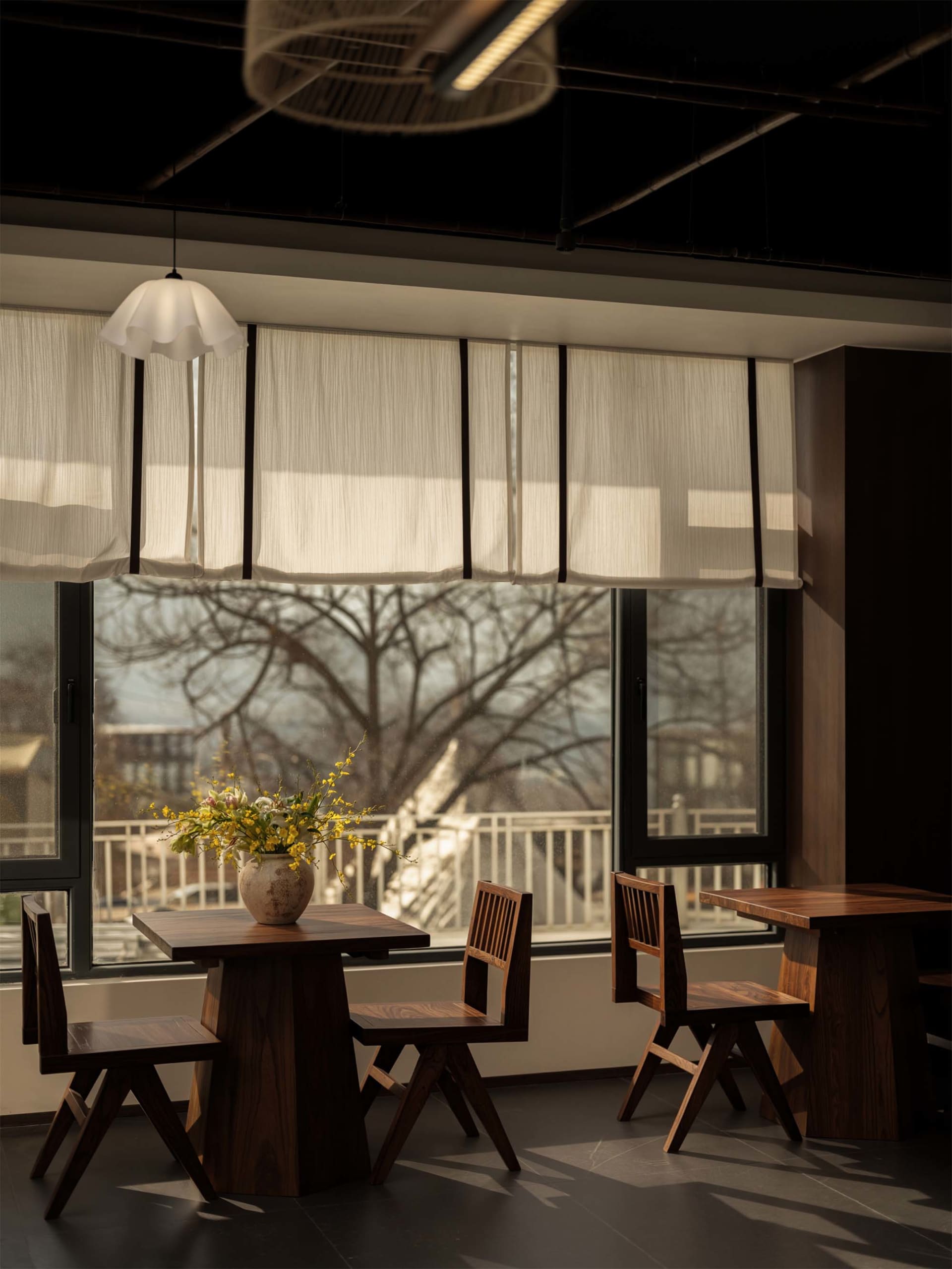 A warm and inviting restaurant dining area with a wooden table and chairs, surrounded by a vase with flowers, in a well-lit space